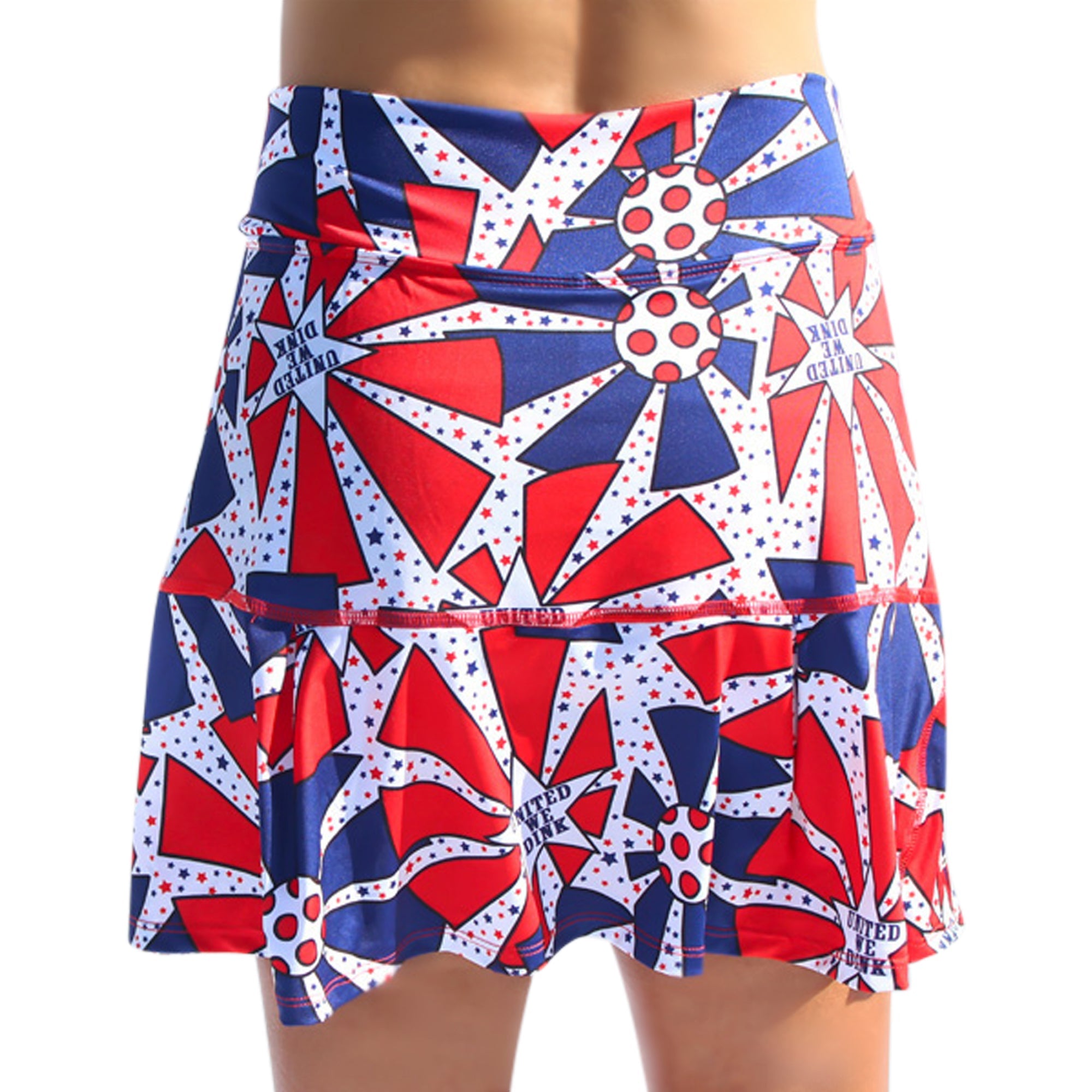 Red, white, and blue pleated skort by Pickleball Bella, with a patriotic star and sunburst pattern and "UNITED WE DINK" text.