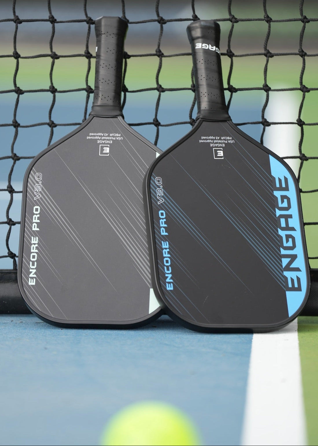 Black True Carbon Skin Encore Pro V3.0 pickleball paddle by EngagePickleball with blue accents, next to one with grey, on a court.
