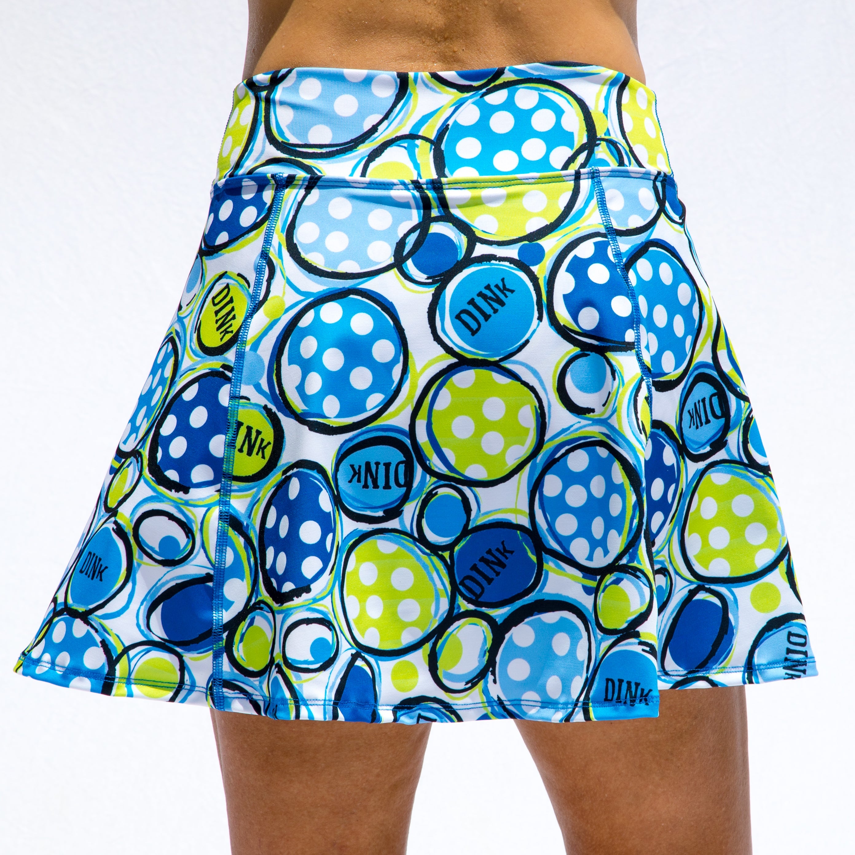 White A-line skort by Pickleball Bella with blue, light blue, lime green polka-dotted circles, and 'DINK' text.