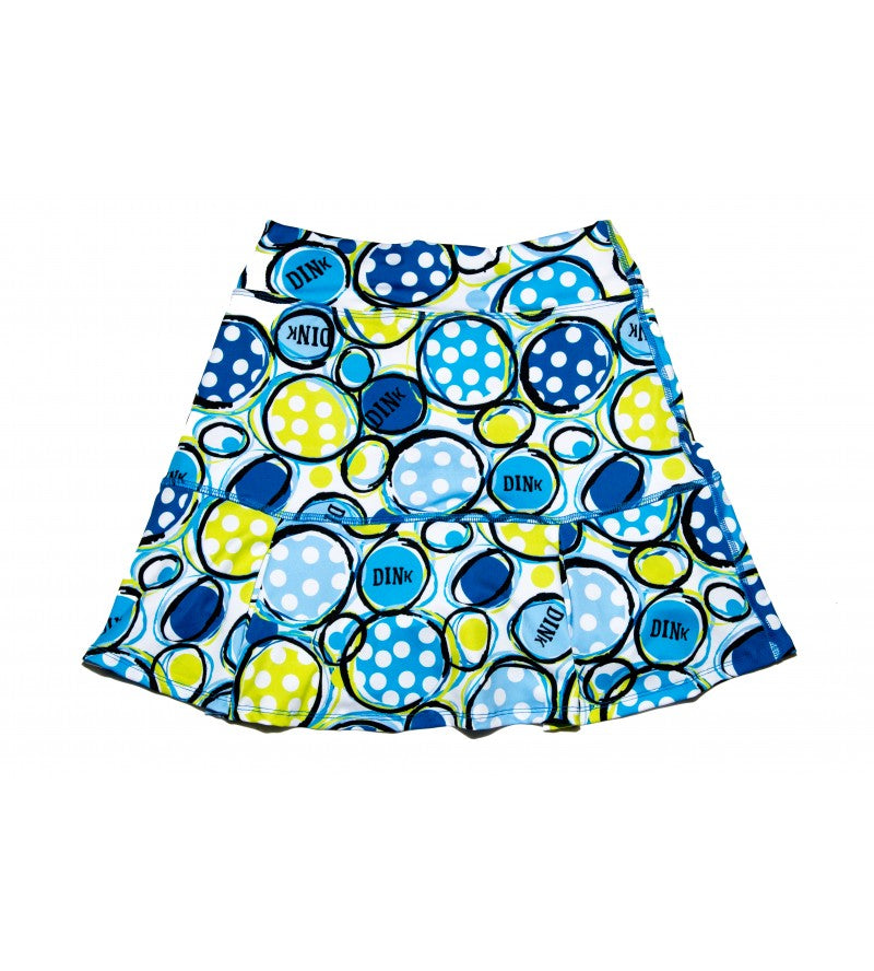 White pleated skort by Pickleball Bella with blue and yellow polka dot circles and 'DINK' text pattern.