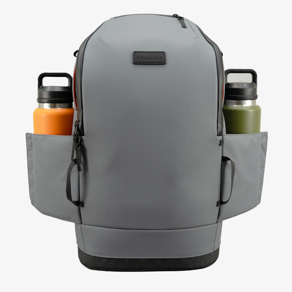 Grey textured Pickleball Backpack by FORWRD, front view, with two side pockets holding orange and green water bottles.