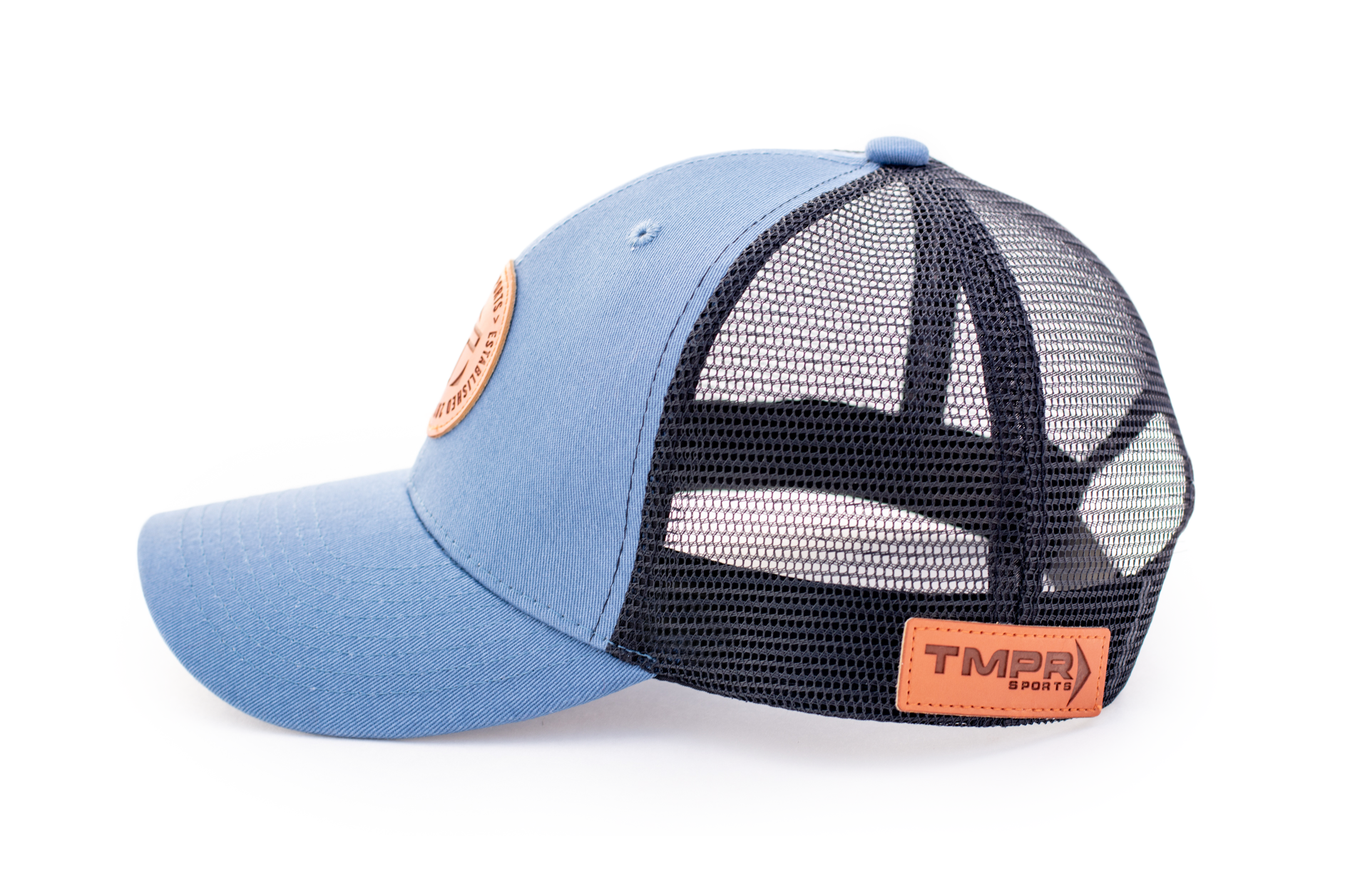Light blue and black mesh trucker cap by TMPR Sports, with a round brown leather patch on the front and a rectangular logo on the back, side view.