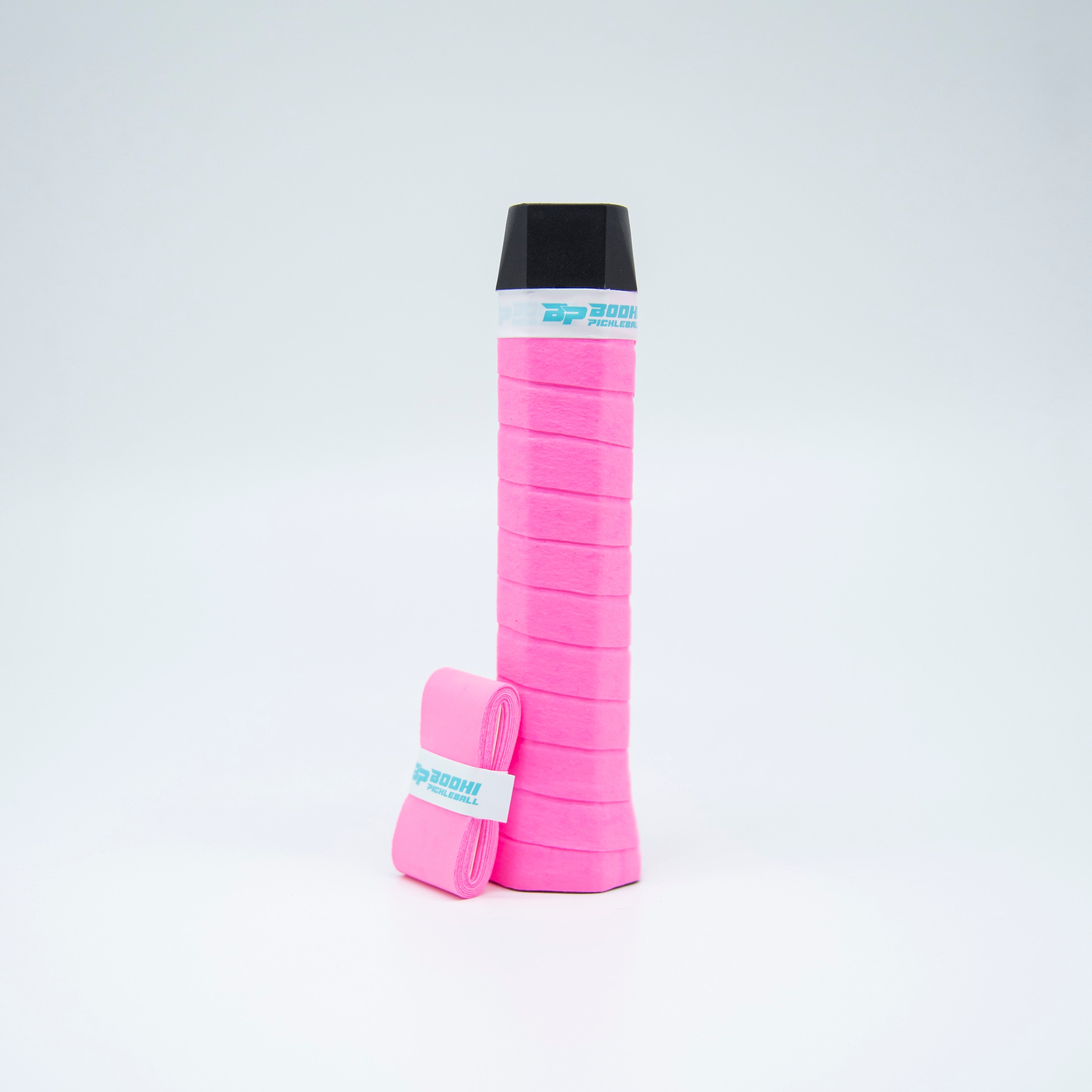 Pink overgrip for a pickleball paddle with the grip wrapped around the handle and an unused overgrip roll to the side.