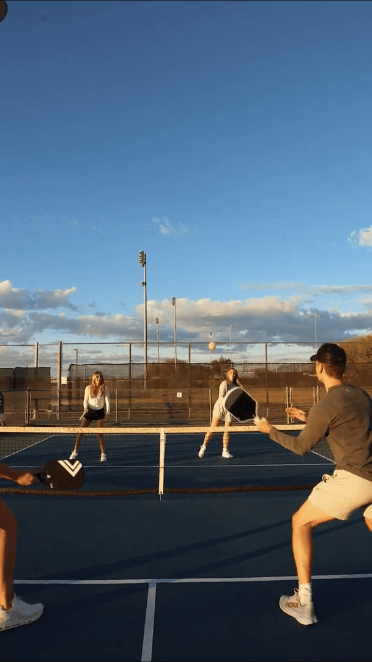 Four people playing pickleball on an outdoor court.