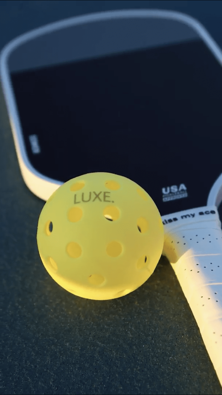 Yellow pickleball, white paddle, black hitting surface.