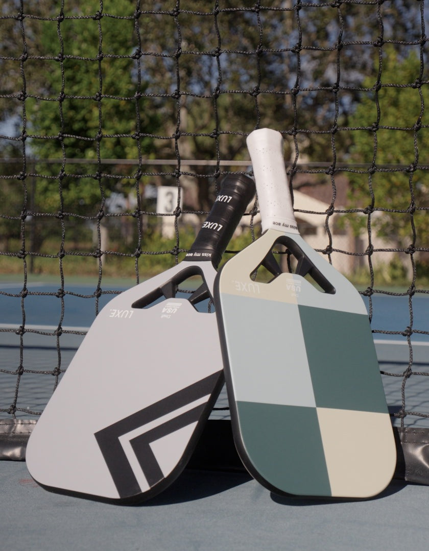 Two pickleball paddles leaning against a net.