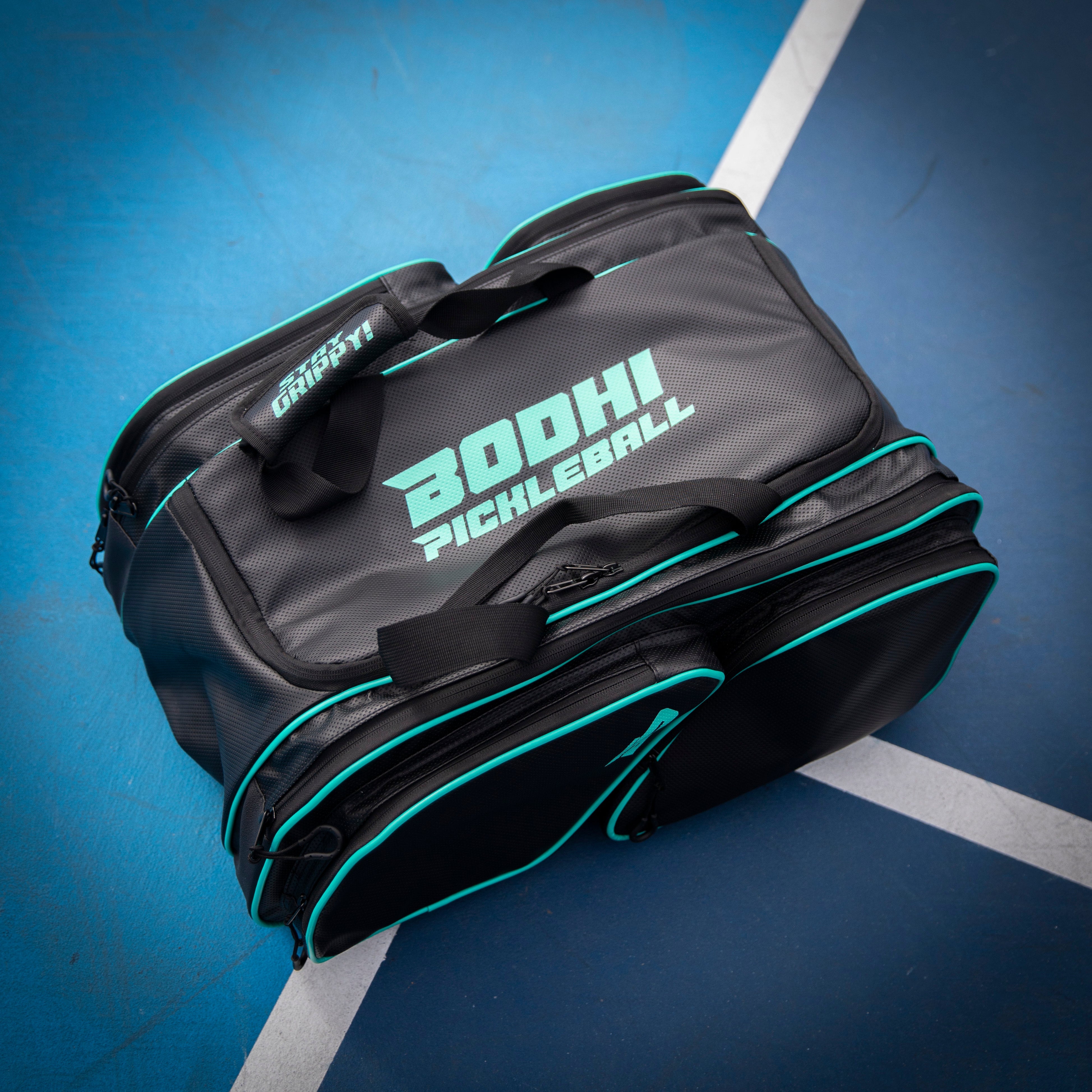 Gray and black pickleball bag with teal accents on a blue court.