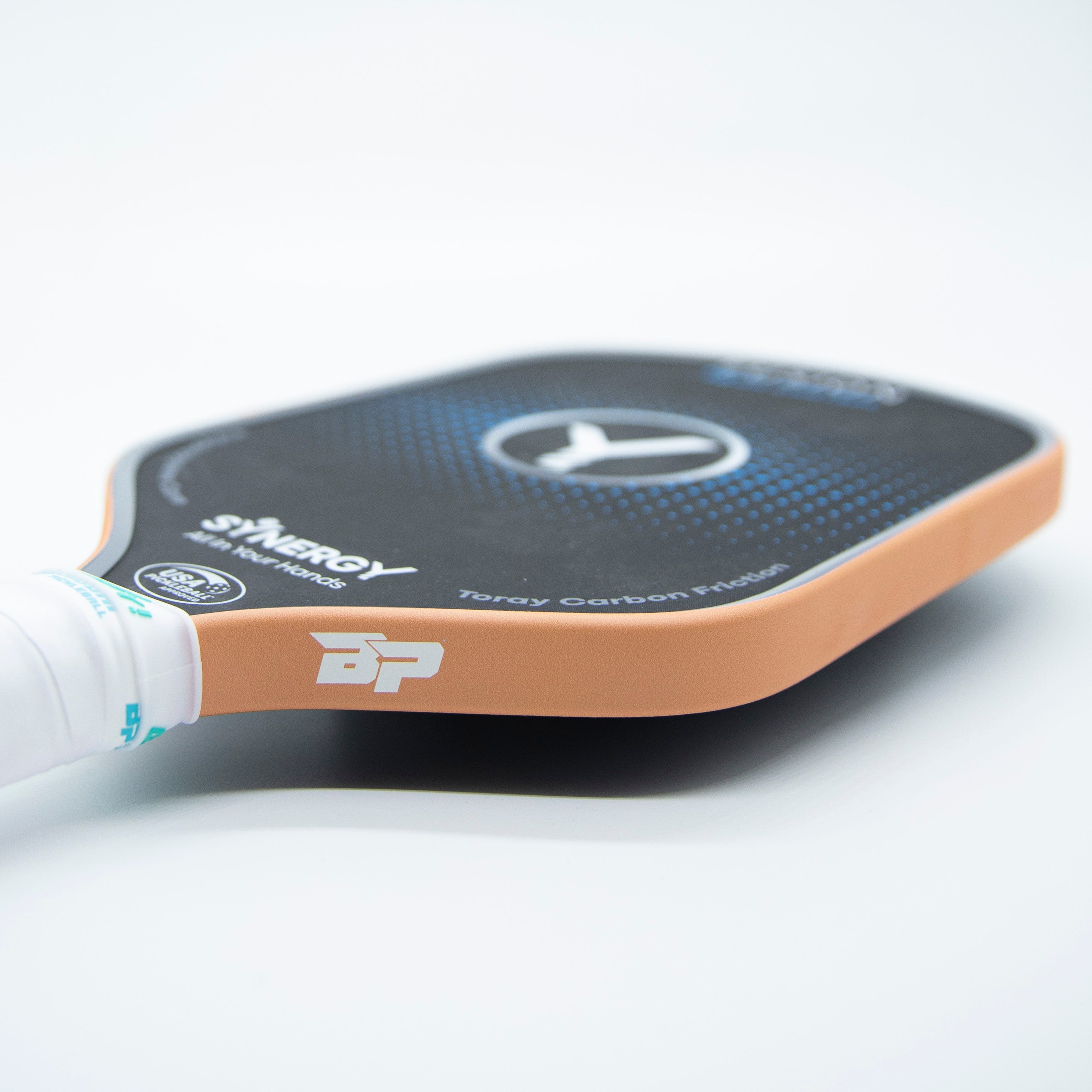 Orange matte pickleball paddle edge tape by DinkersAlley.com, wrapped around a black paddle with a white grip.