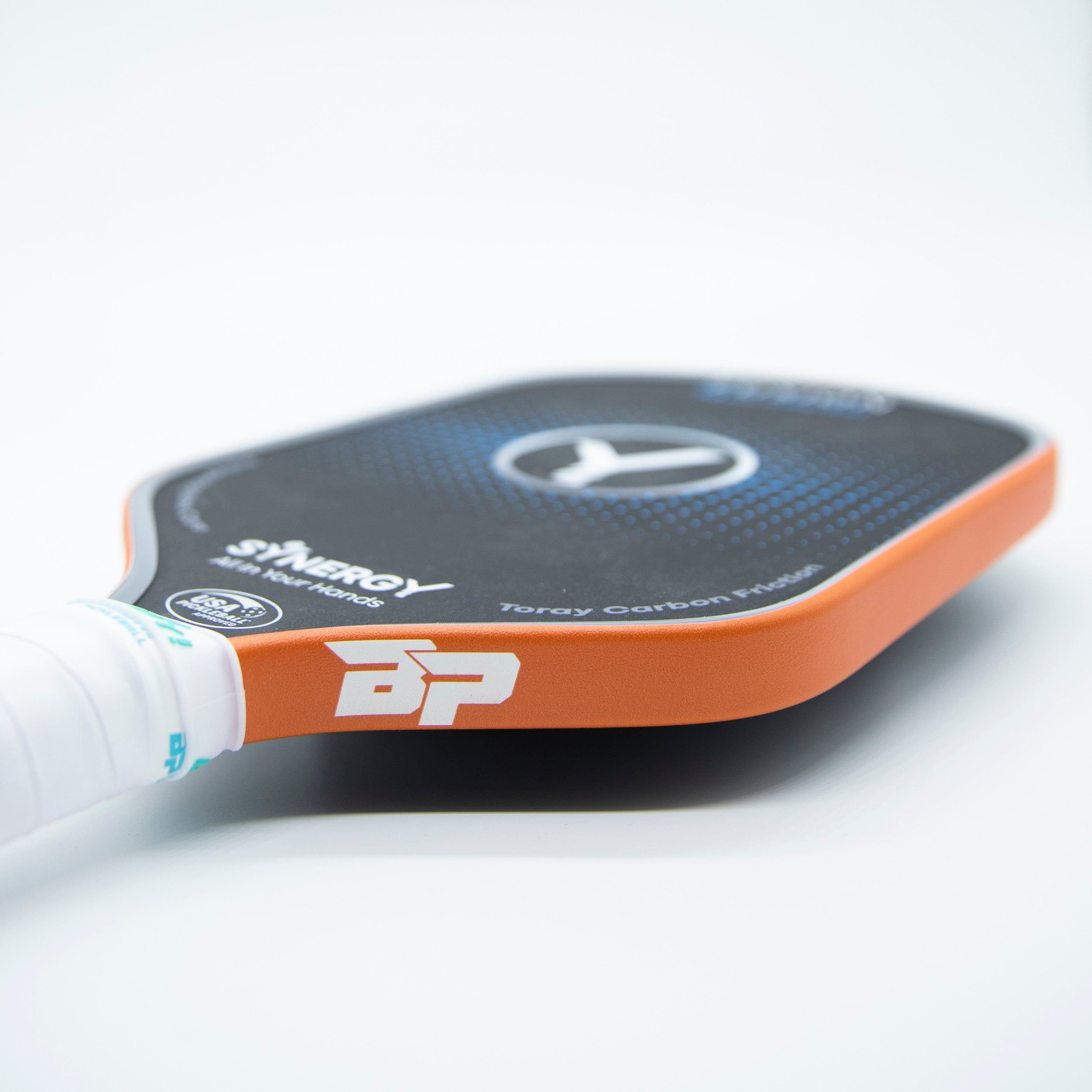 Angled side view of a black pickleball paddle with bright orange edge tape from DinkersAlley.com, featuring a white grip and 'BP' logo.