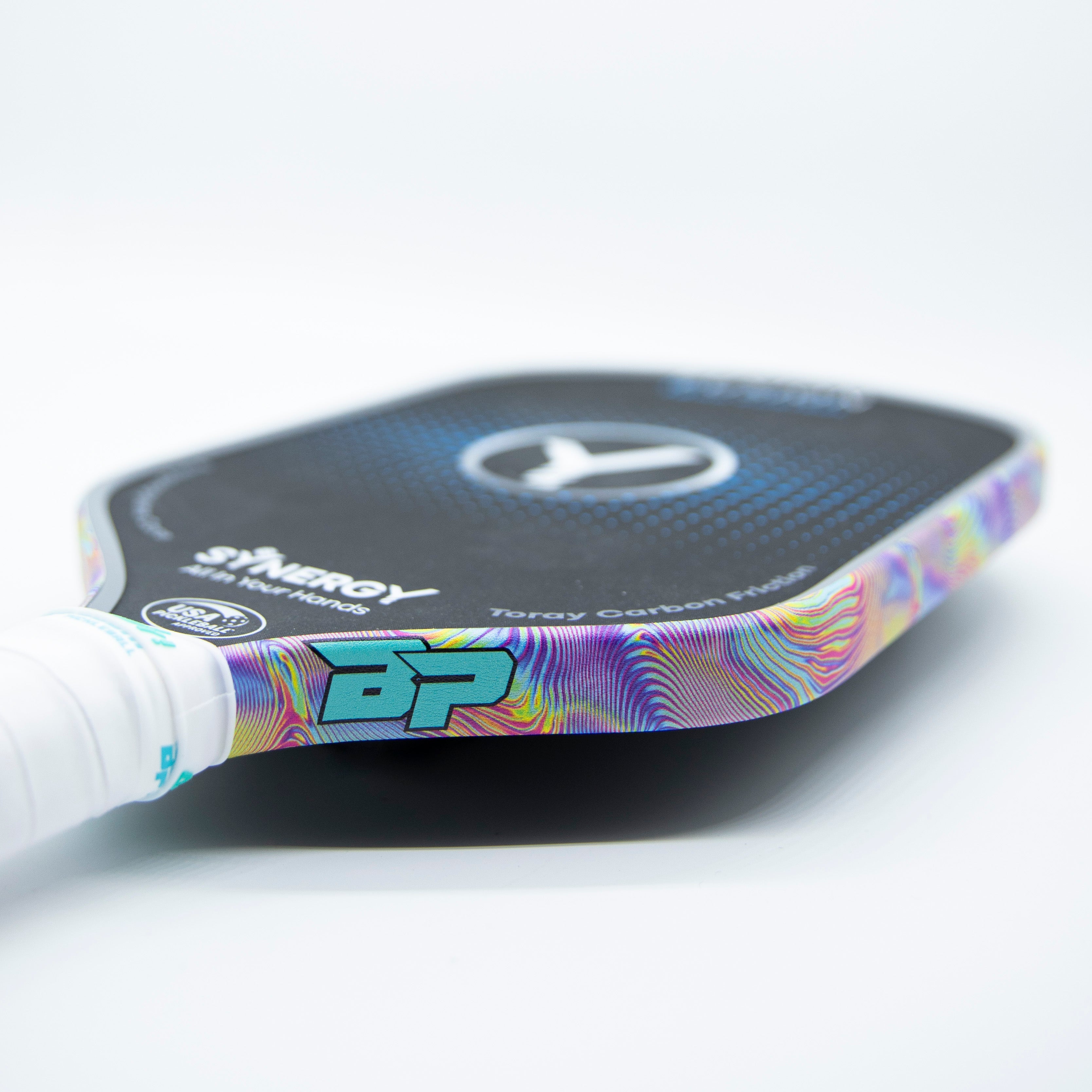 Close-up view of a pickleball paddle with a colorful psychedelic design, a white grip, and a black face.