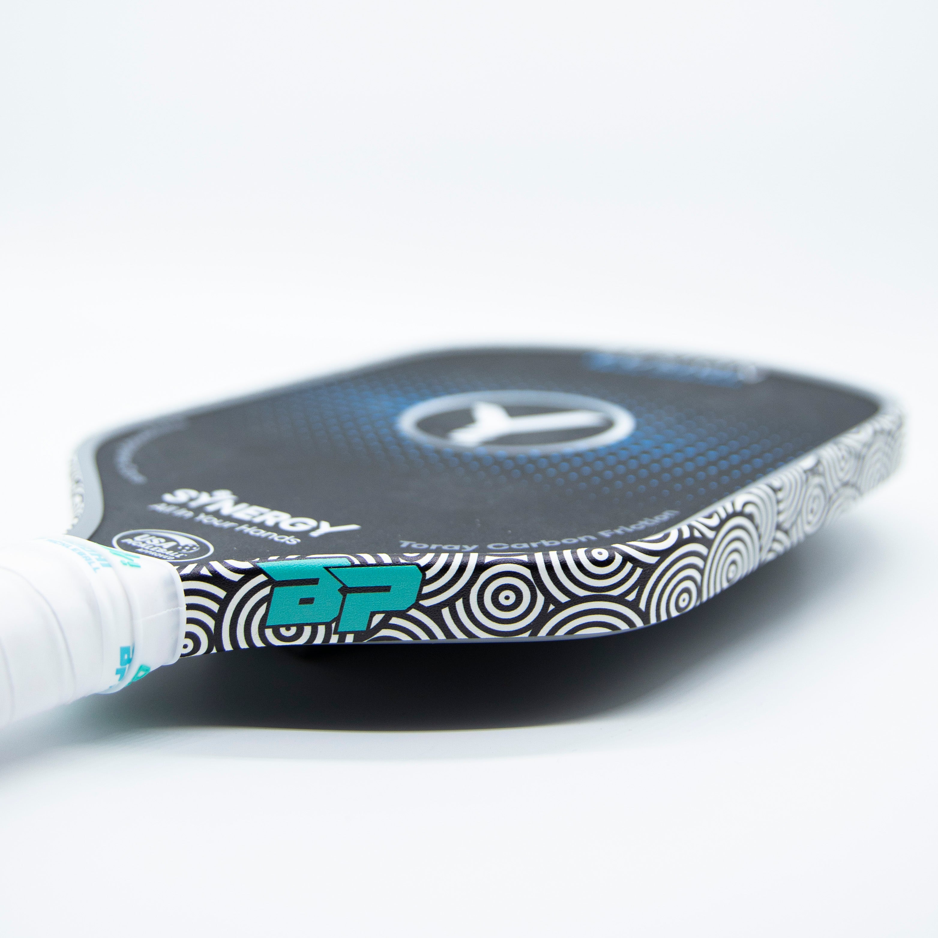Close-up of a black and white pickleball paddle with teal accents and a white grip.