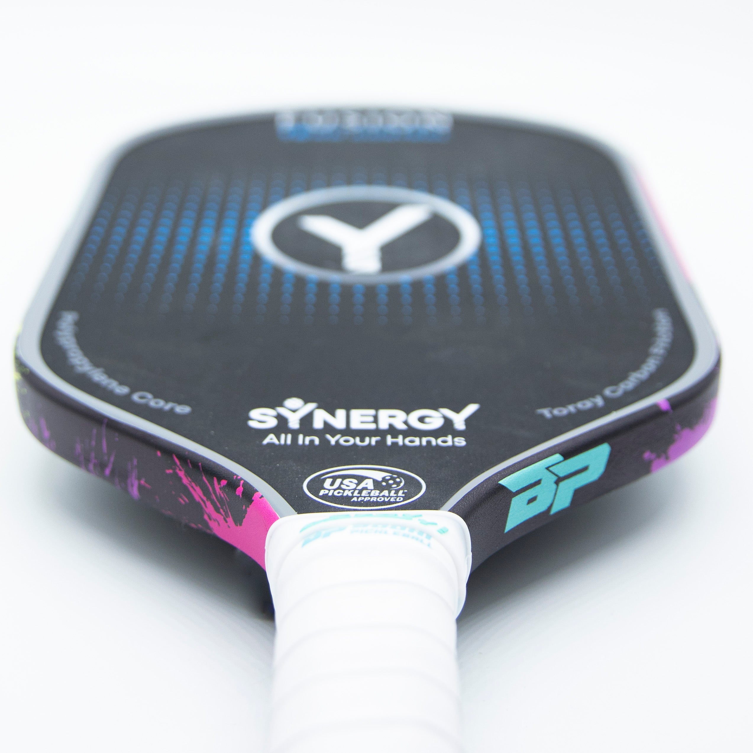 Pickleball paddle with a black face, blue dots, a white logo, and a white handle grip.