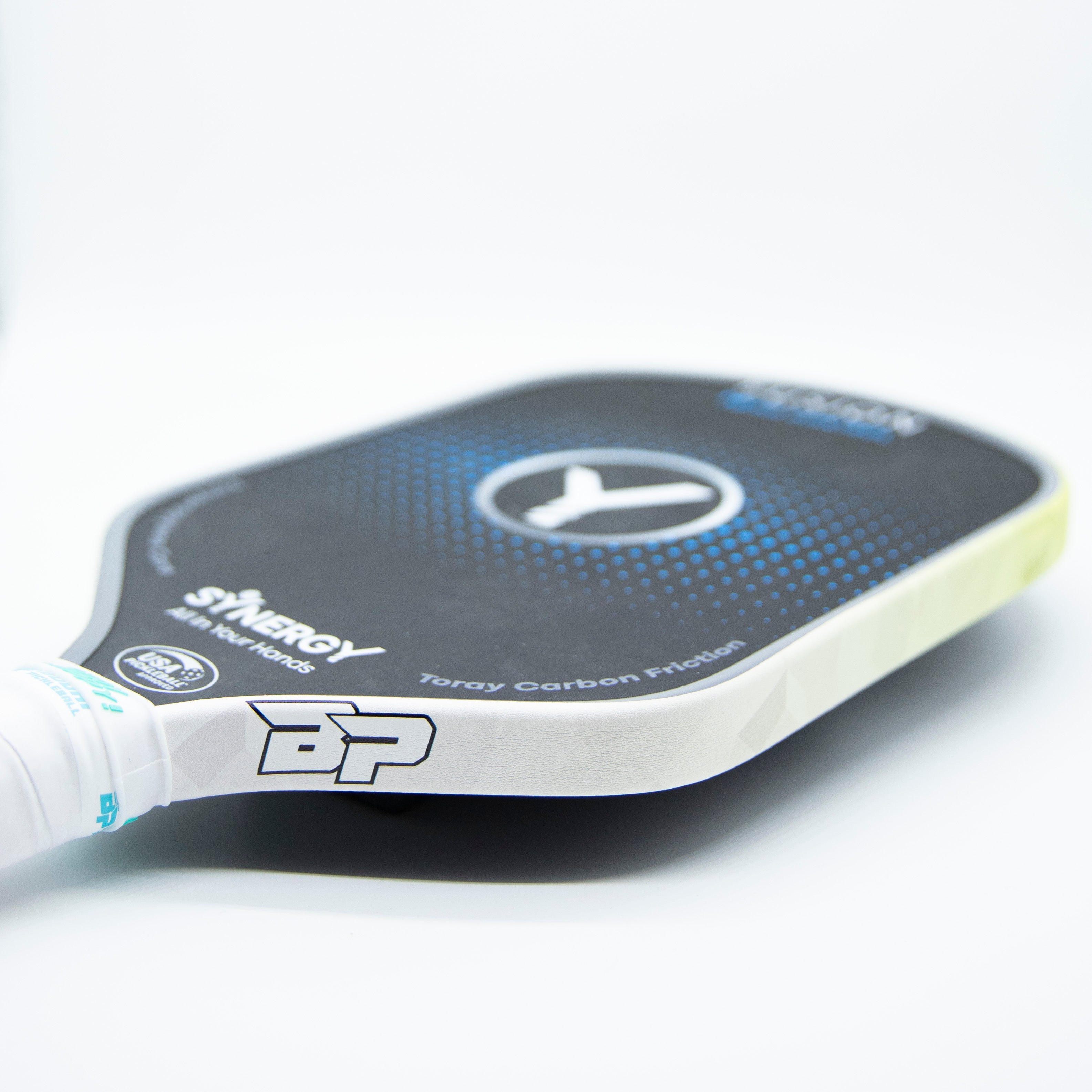 Close-up of a black and blue Synergy Pickleball paddle with a white handle.