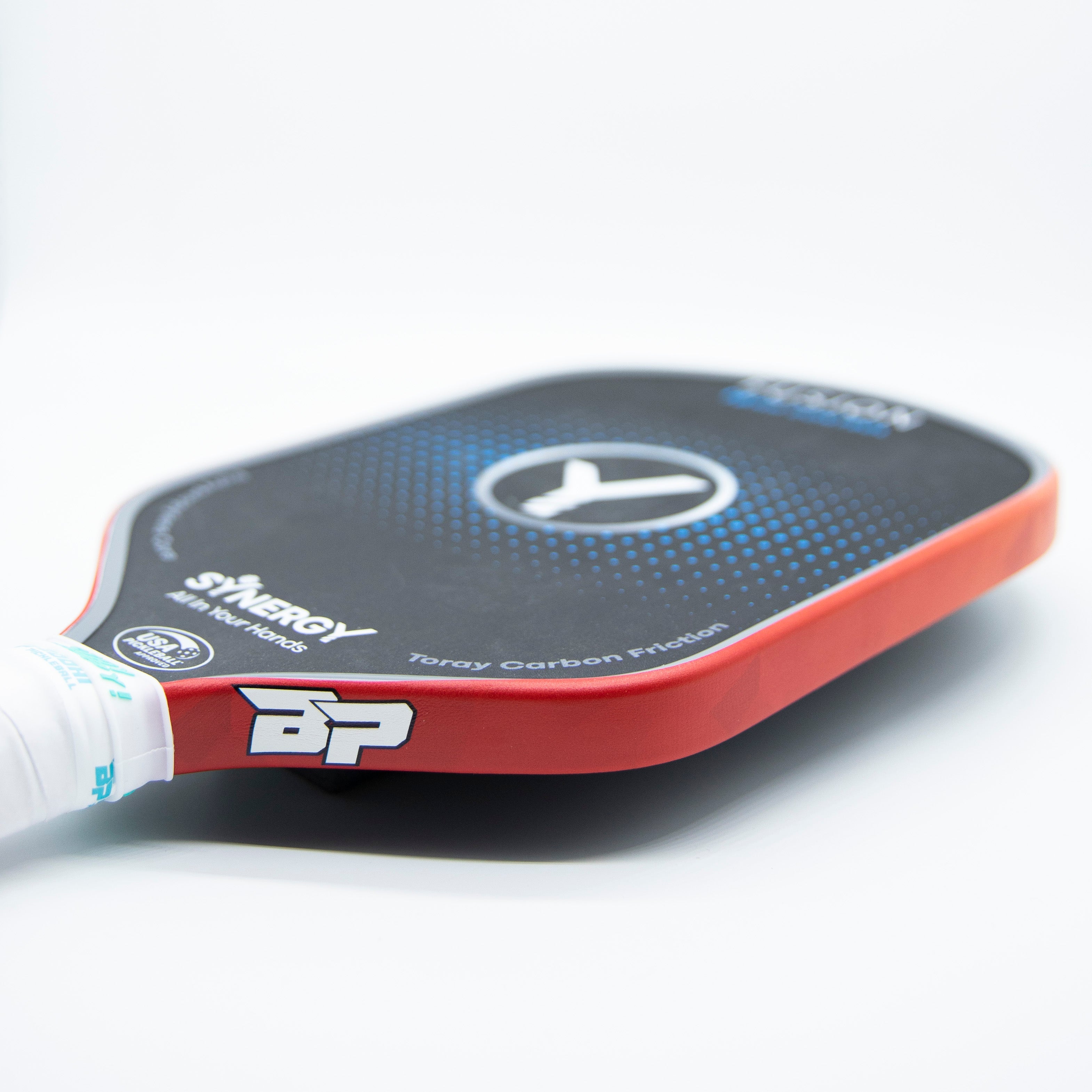 Close-up of a red and black pickleball paddle with a white grip.