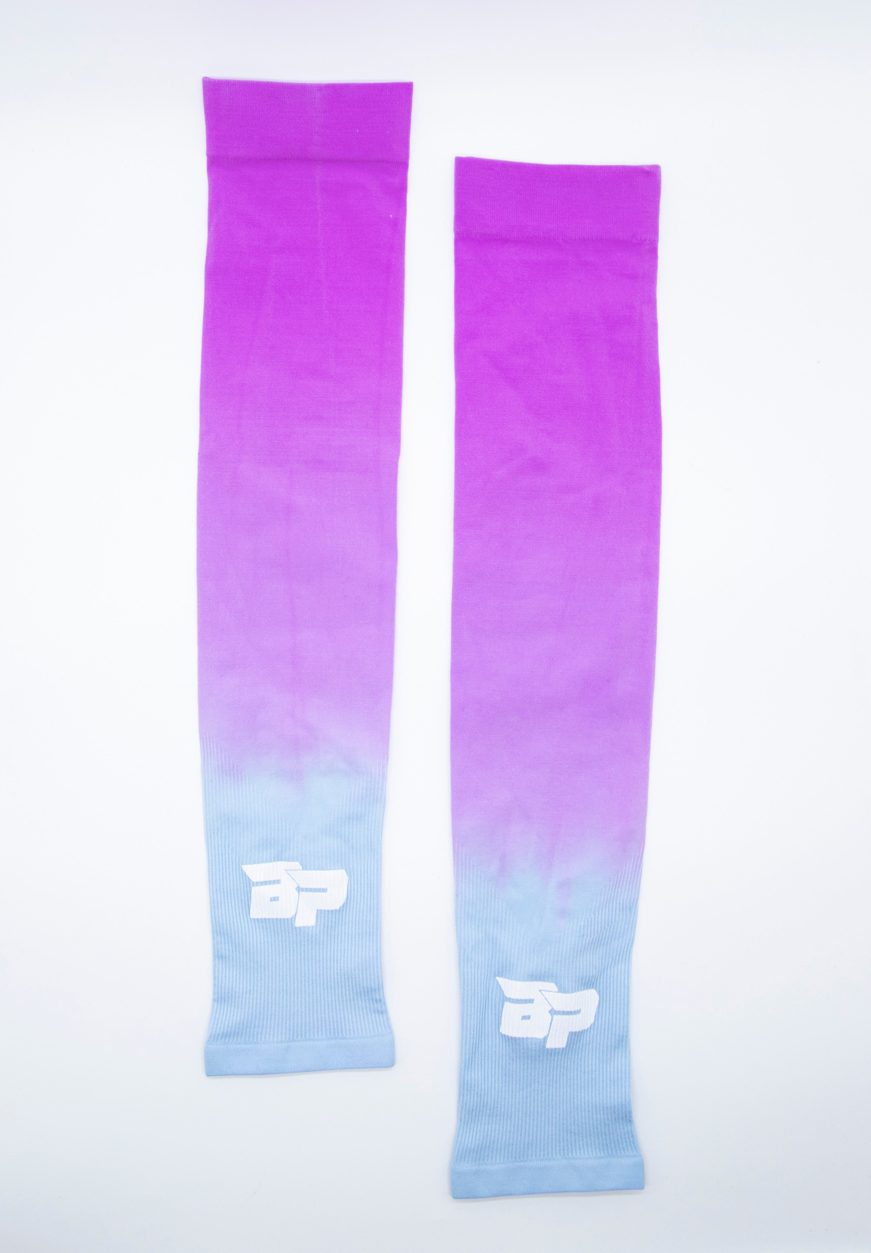 Pair of gradient purple and blue performance arm sleeves by Bodhi Pickleball, with a white BP logo and ribbed texture.