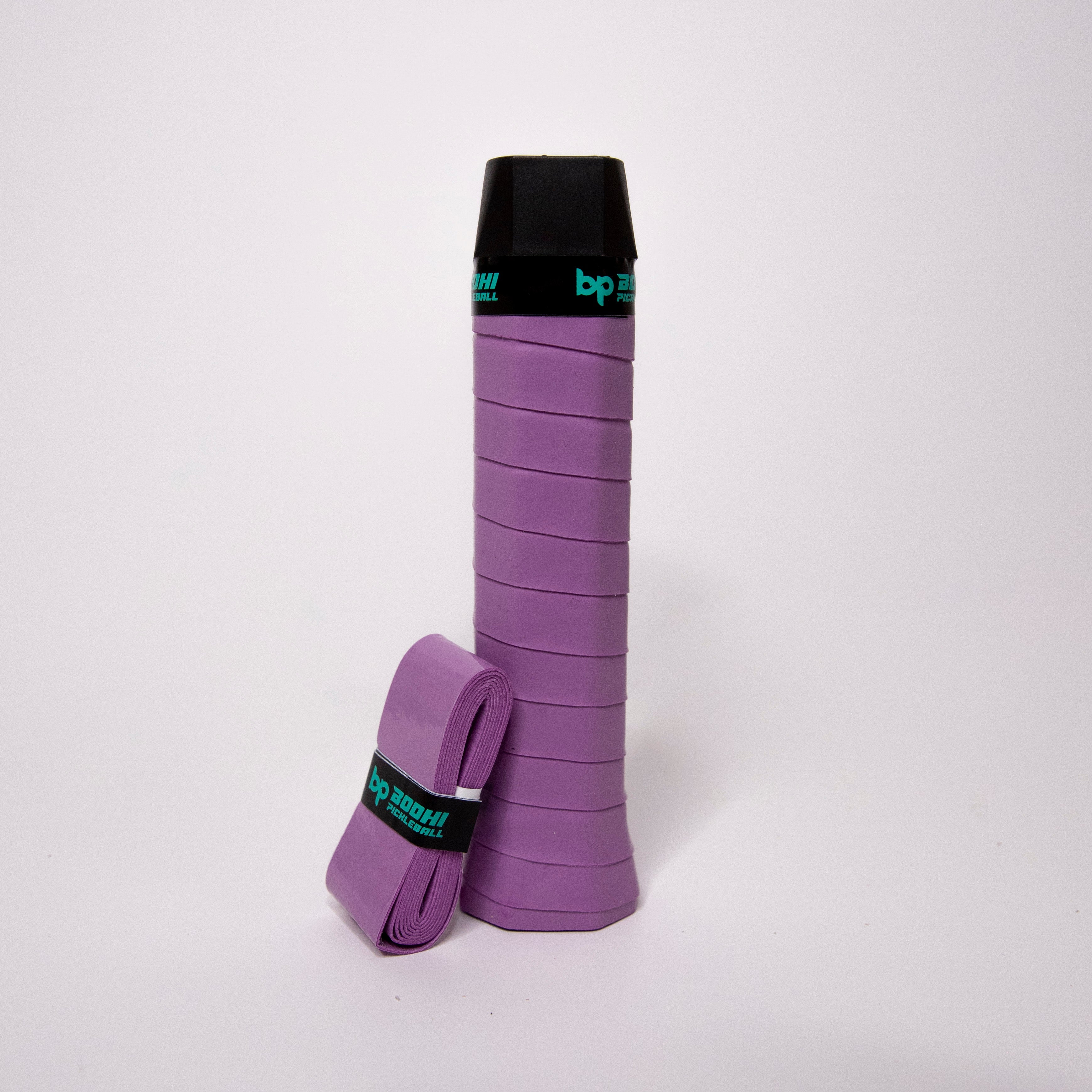 Purple pickleball paddle grip and a partially wrapped replacement grip with a black band.