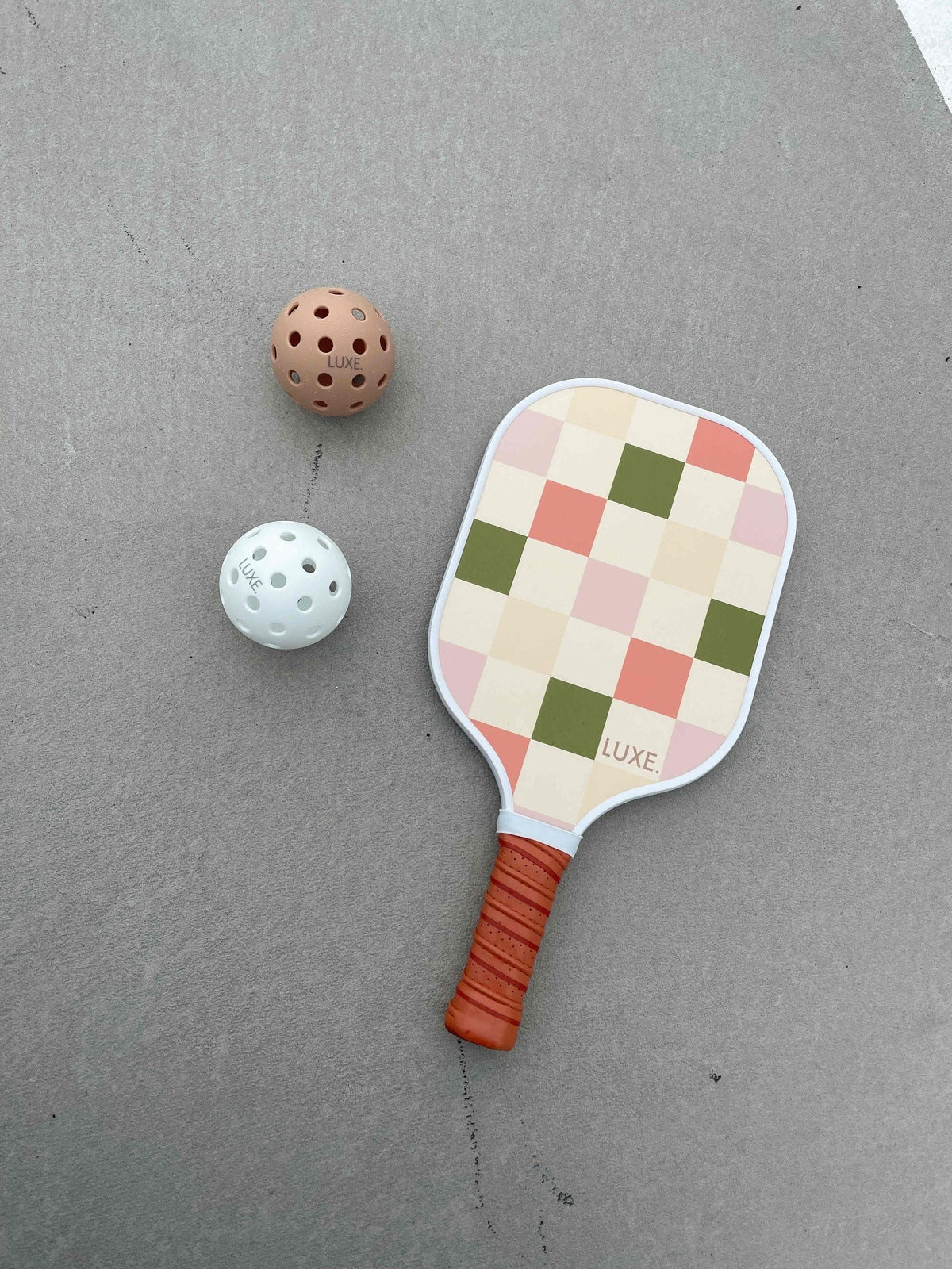 Pickleball paddle with checkered design and two pickleballs.