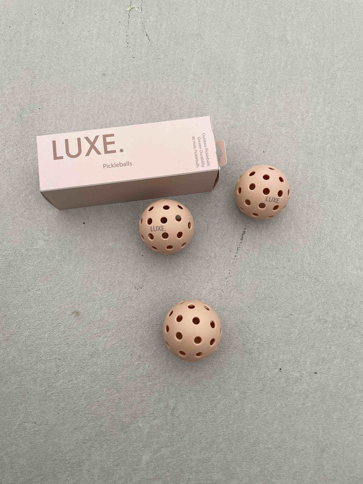 Box of pink pickleballs with three pickleballs.