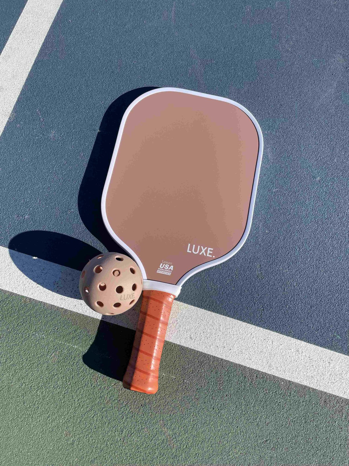 Pickleball paddle and ball on a court.
