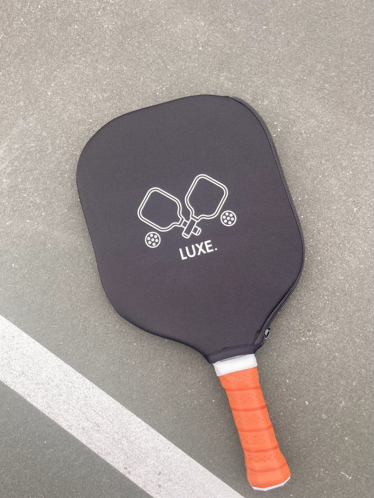 Pickleball paddle with black cover and orange handle.