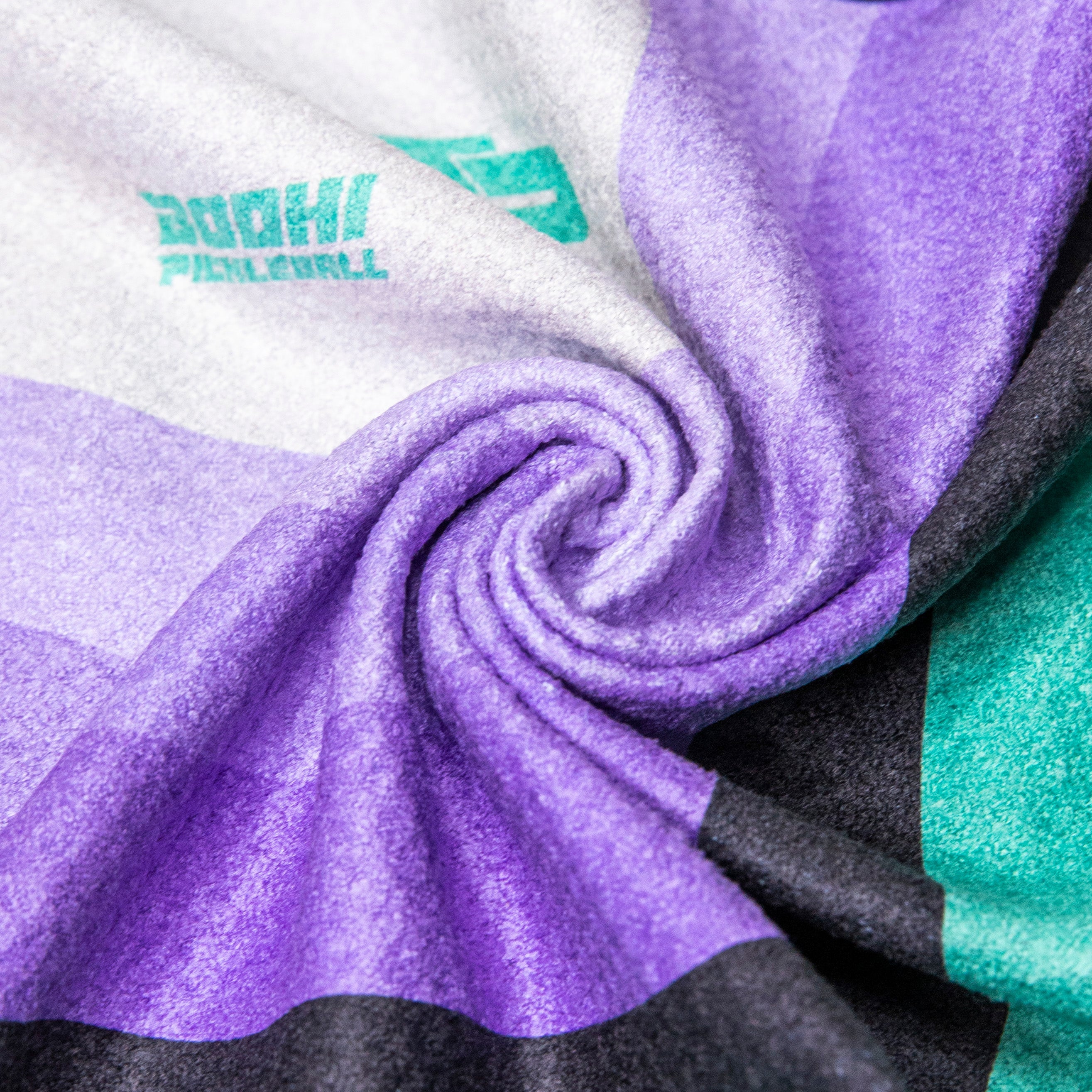 Folded blanket with purple, gray, black, and teal stripes.