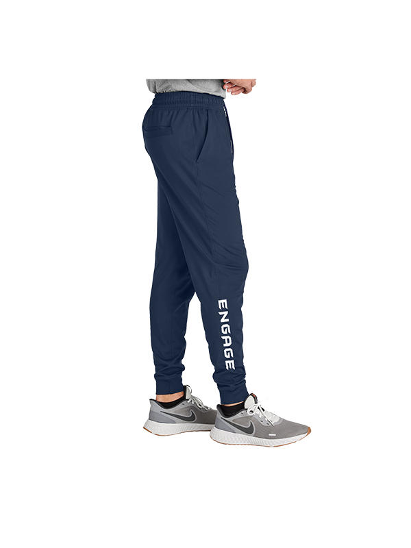 Navy blue Men's Valor Warmup Pants by EngagePickleball, featuring white ENGAGE text vertically on the right leg, worn with a grey t-shirt and sneakers, side view.