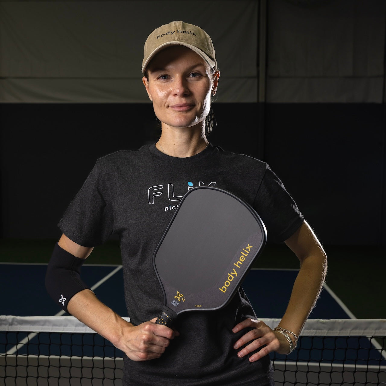 Woman in hat holding a pickleball paddle.