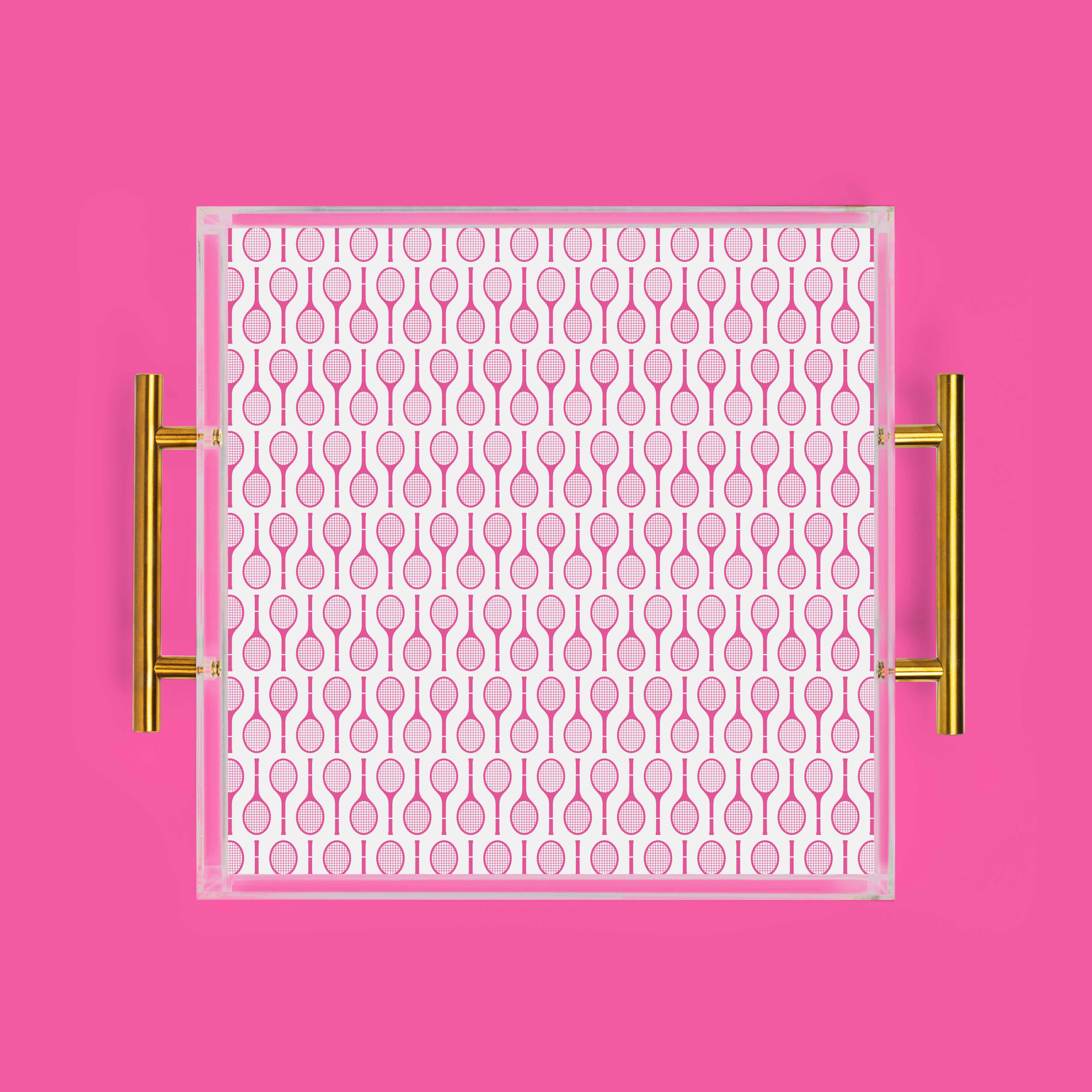 Pink tray with tennis racket pattern and gold handles on pink background.