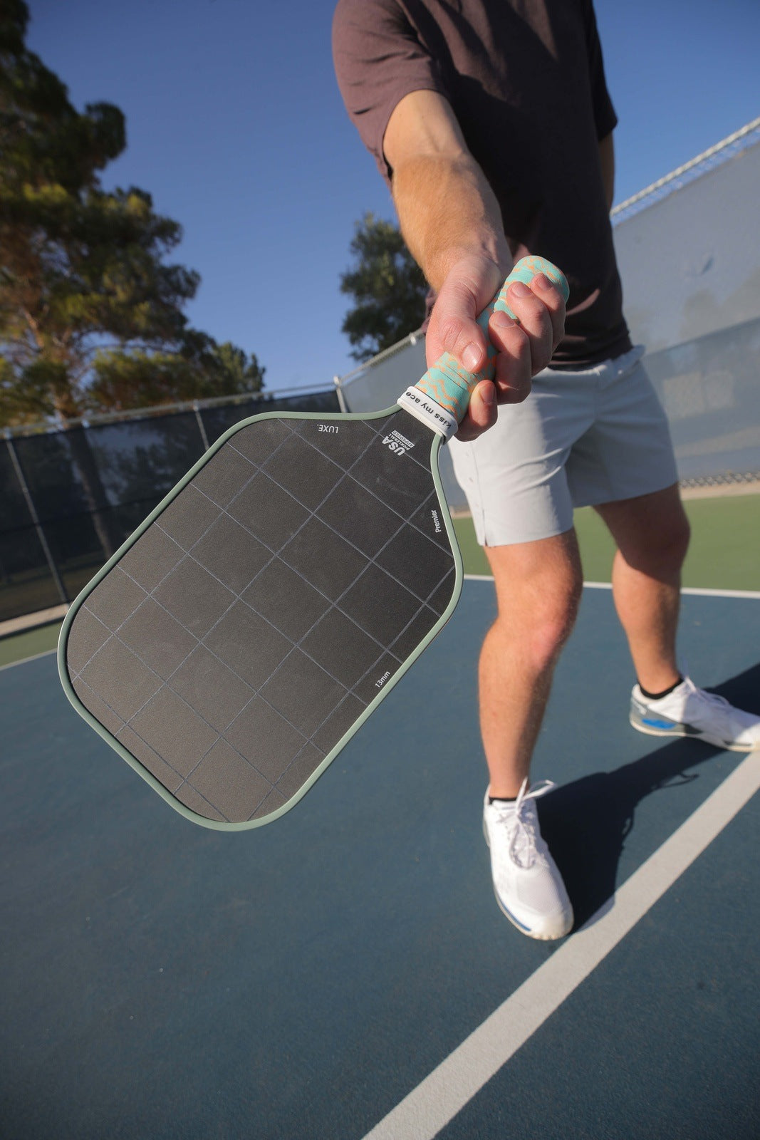 A man holding a pickleball paddle on a tennis court.