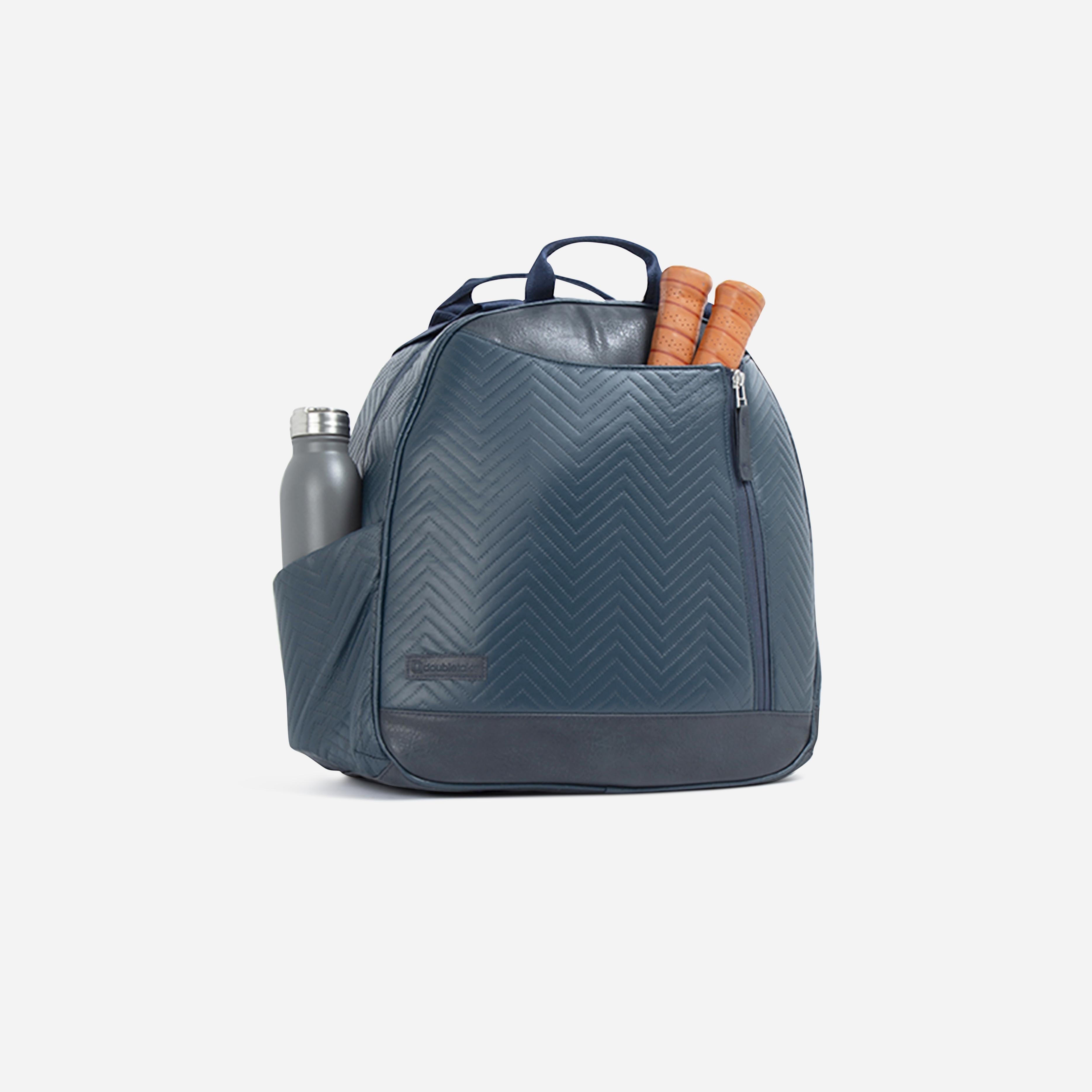 Dark blue quilted pickleball backpack by Doubletake, featuring a chevron pattern, a side pocket with a gray water bottle, and two visible paddle handles.