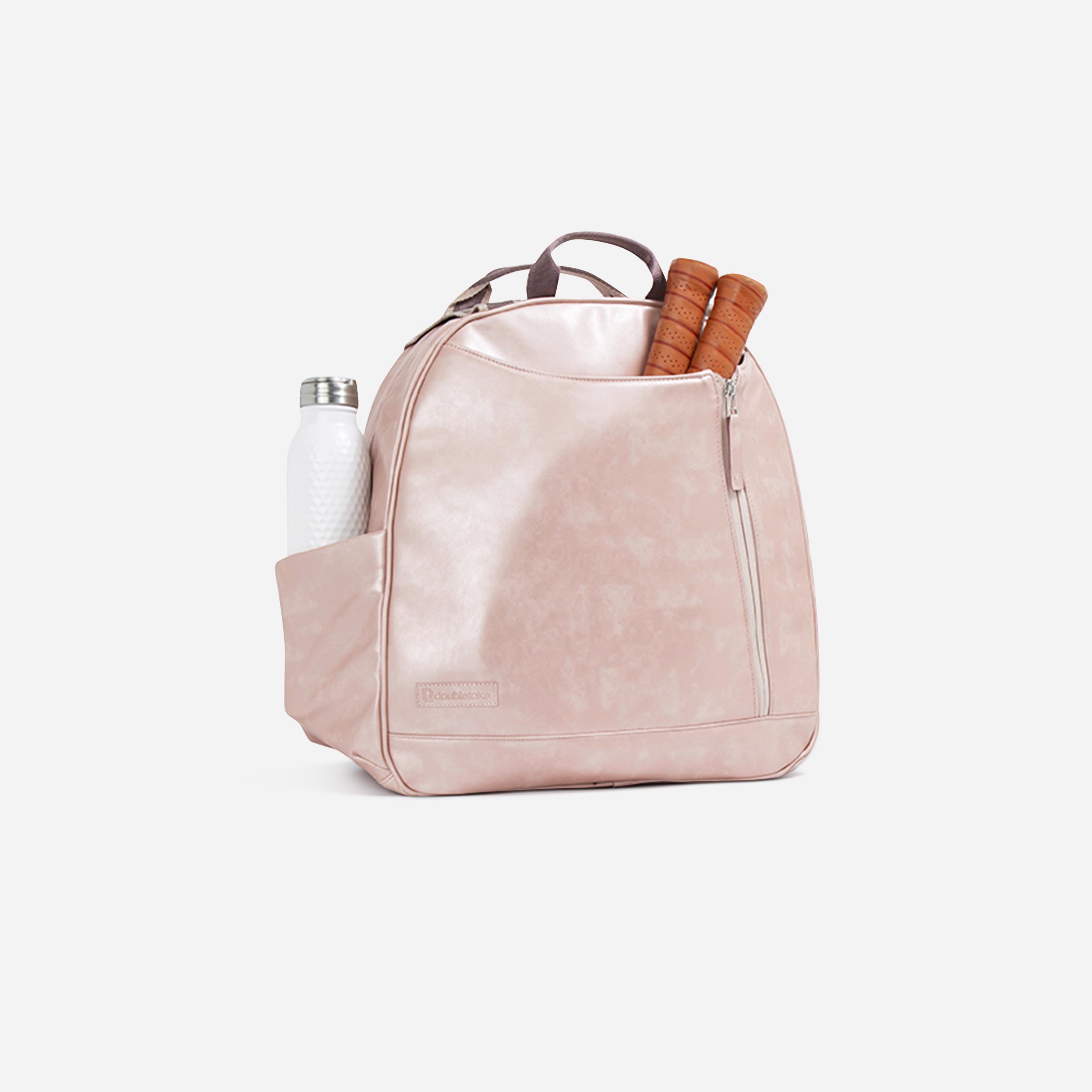 A shimmering pink pickleball backpack and tote by Doubletake, with an embossed logo, water bottle, and paddle grips.