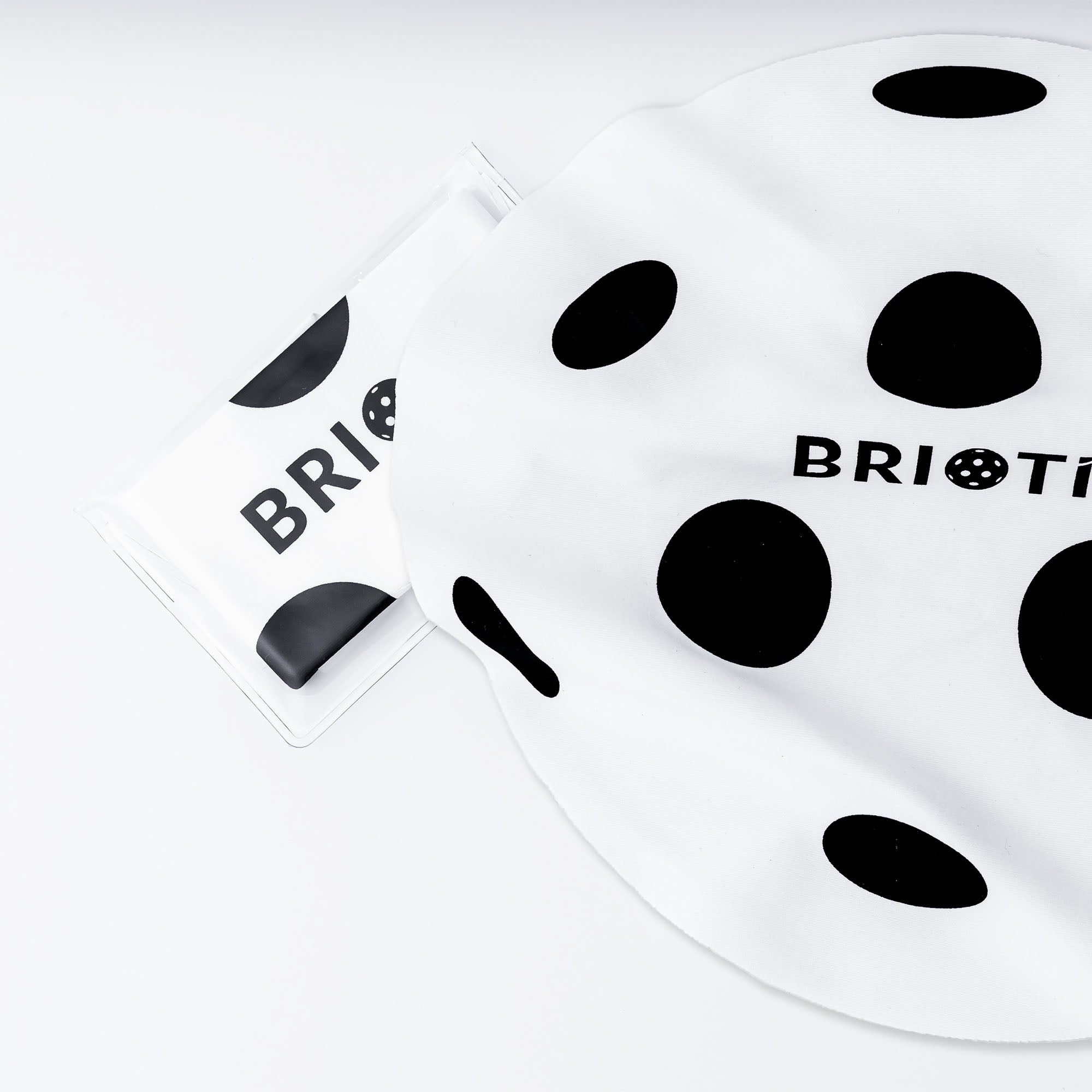 White swim cap with black polka dots and the brand "BRIOTI" on it.