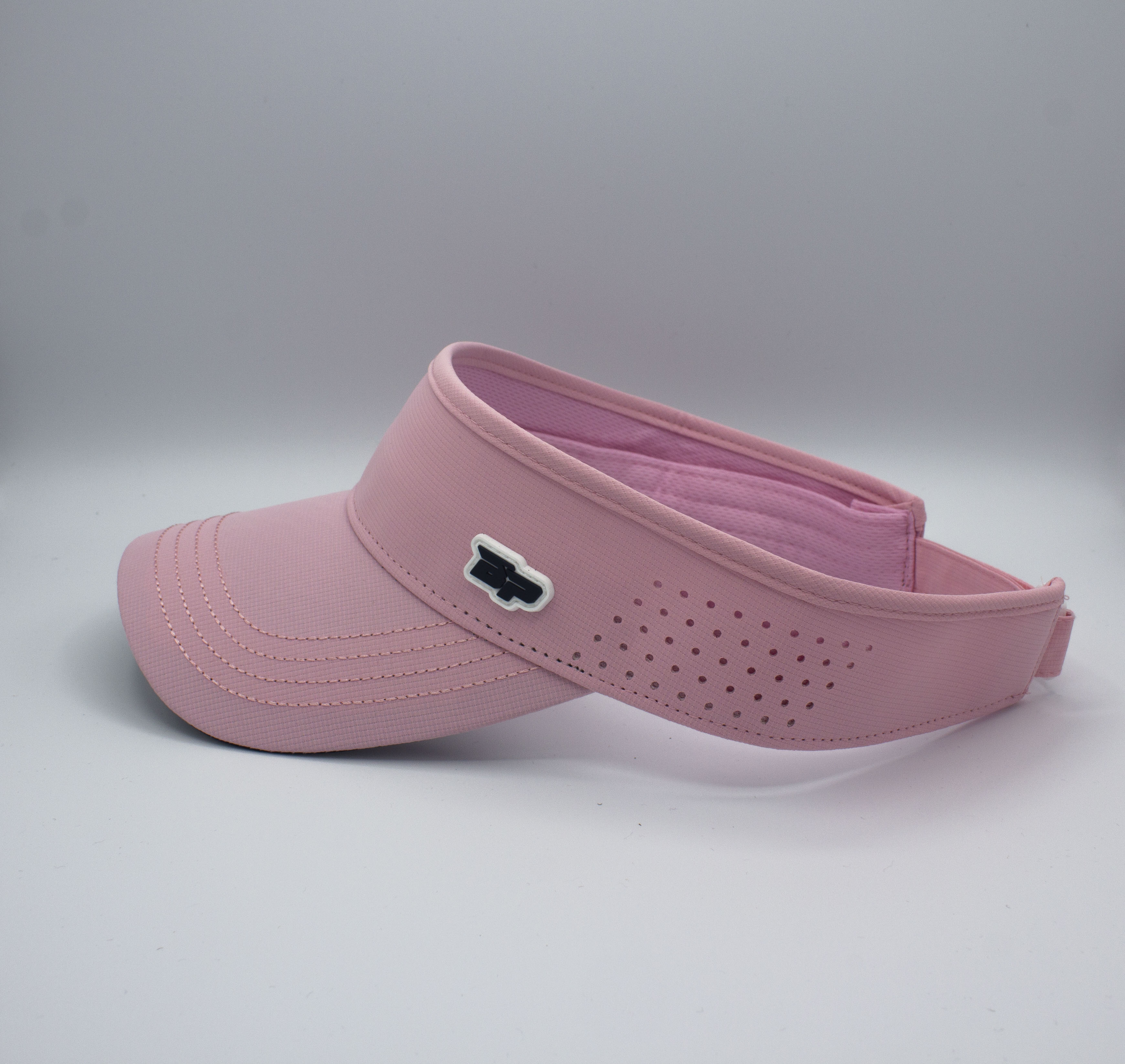 A pink visor with a dark logo and ventilation holes is displayed against a light gray background.