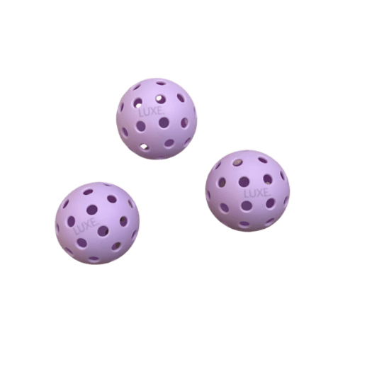 Three purple pickleballs with the word "LUXE" on each.