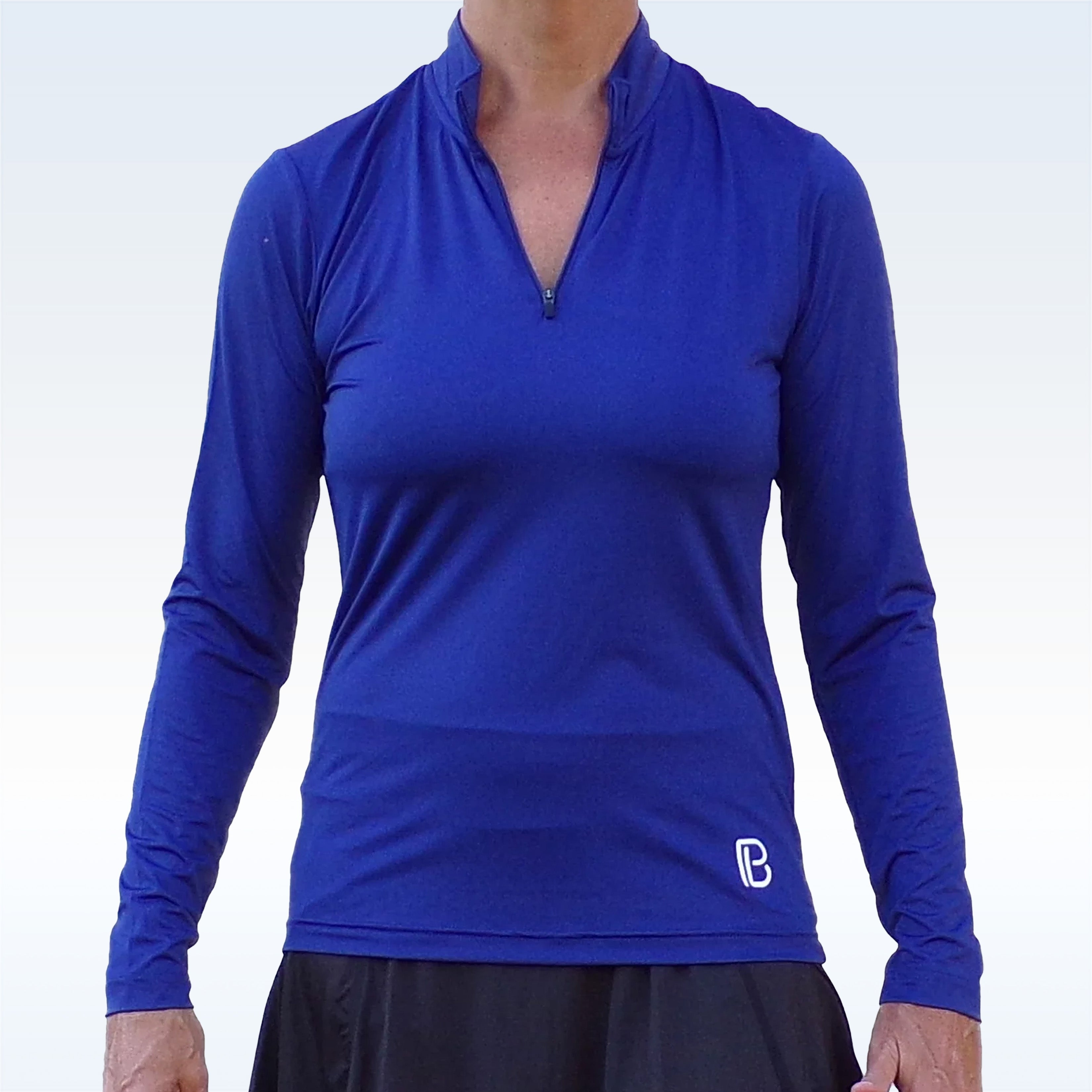 Navy blue long sleeve 1/4 zip pullover by Pickleball Bella with a small white "PB" logo on the left hip, worn with a black skirt.