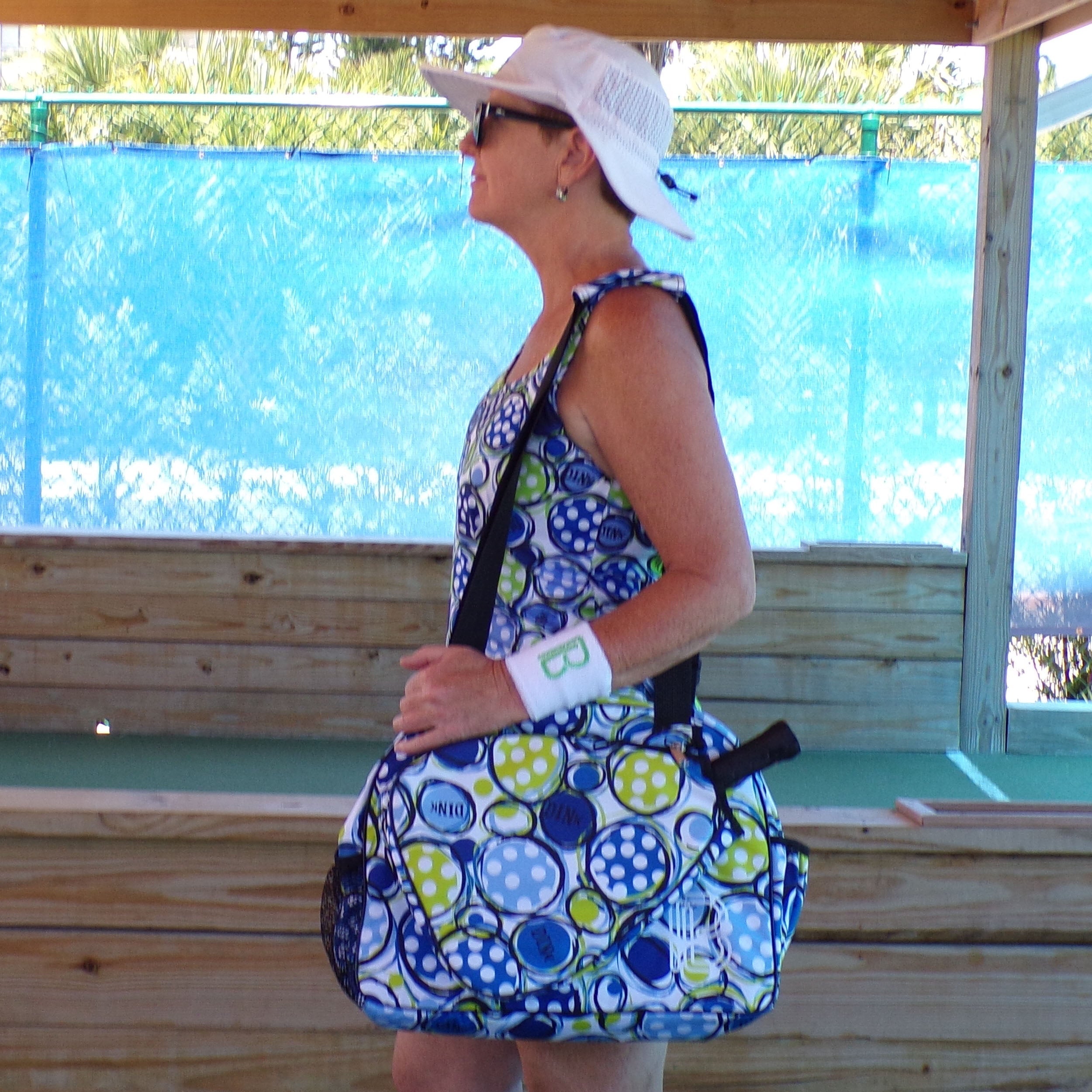 Blue, green, and white polka dot racerback tank by Pickleball Bella, worn by a woman with a matching bag in side view.