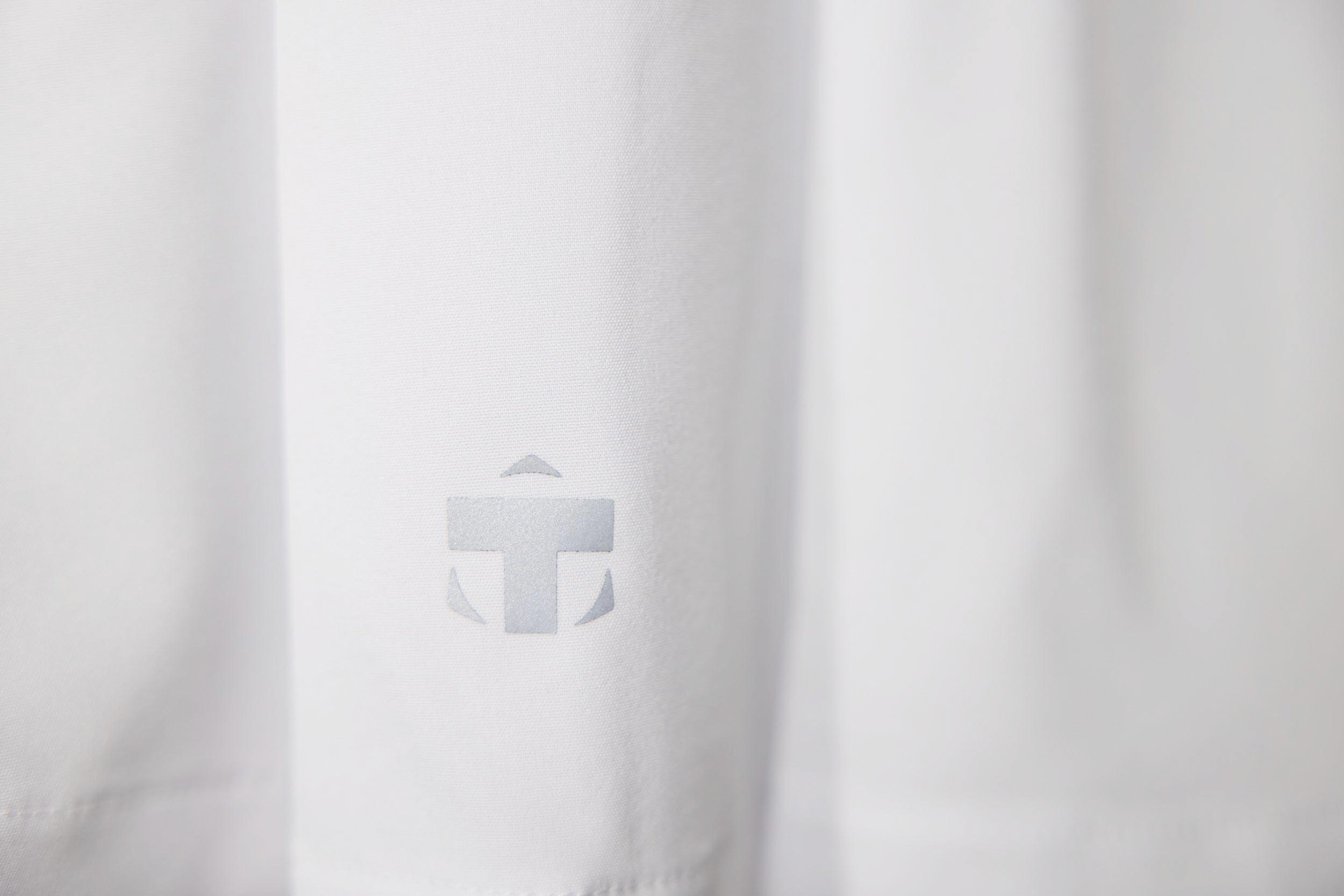 White skort by TMPR Sports, showing a subtle fabric texture and a gray reflective logo.