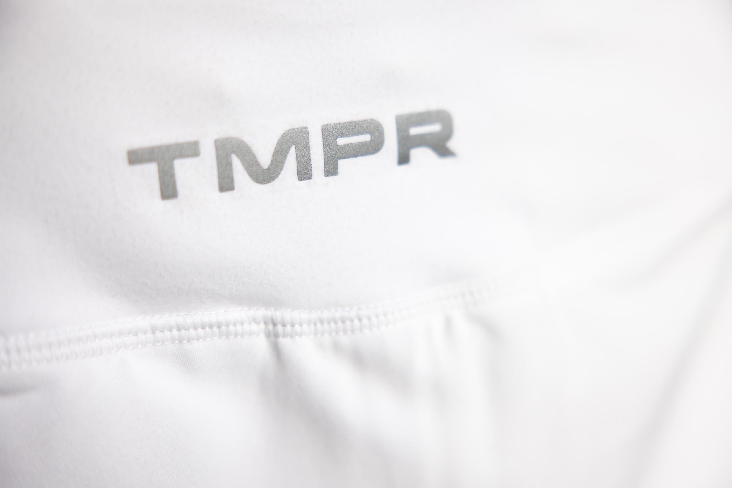 White Performance Mid-Rise Skort by TMPR Sports, featuring a grey "TMPR" logo and a finely stitched seam.