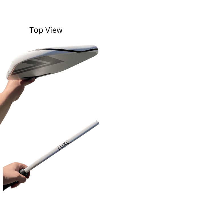 Top view of a white paddle and white stick labeled "LUXE" held by hands against a green background.