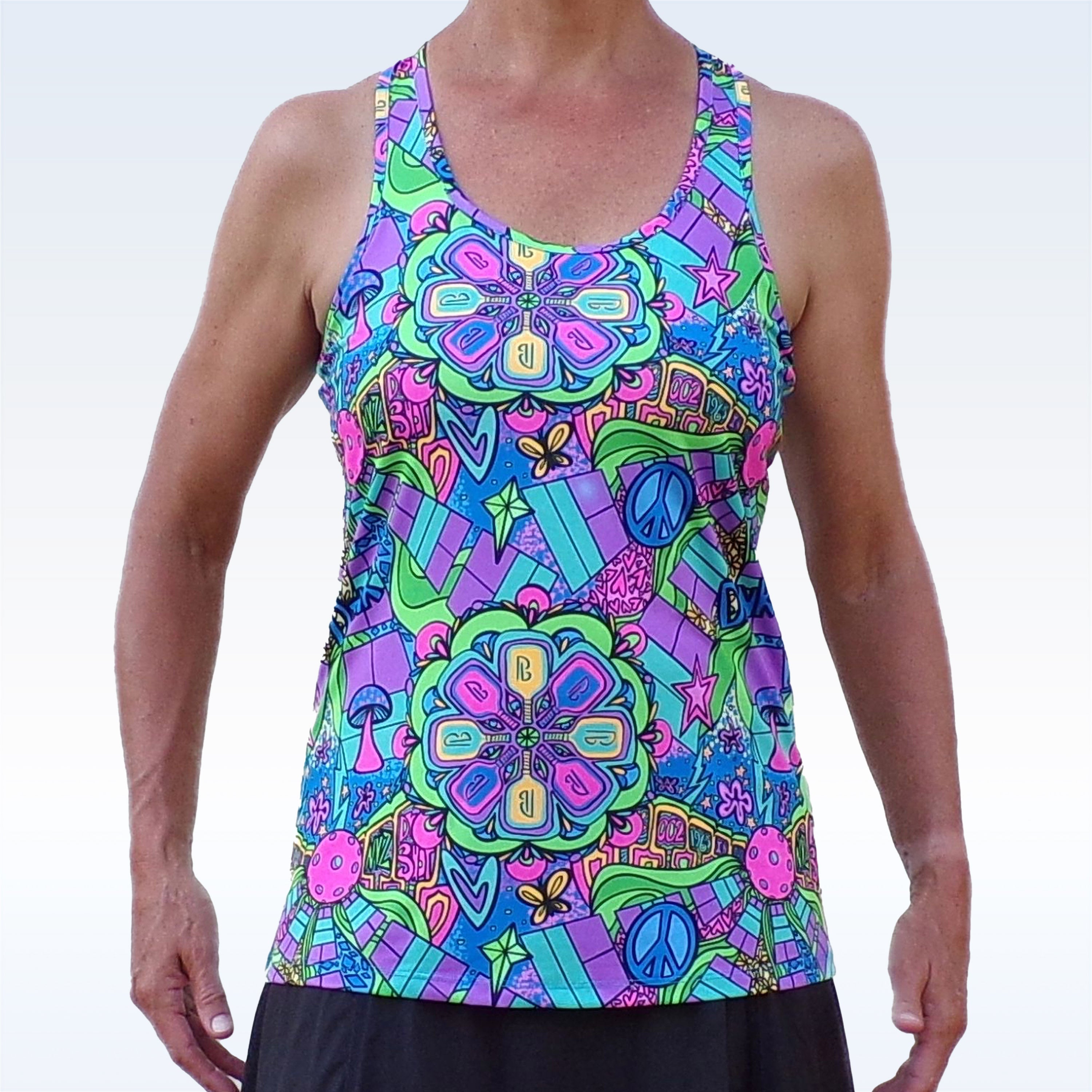 Groovy multi-colored racerback tank top by Pickleball Bella, featuring psychedelic paddles, peace signs, stars, and mushrooms, worn with a black skirt.