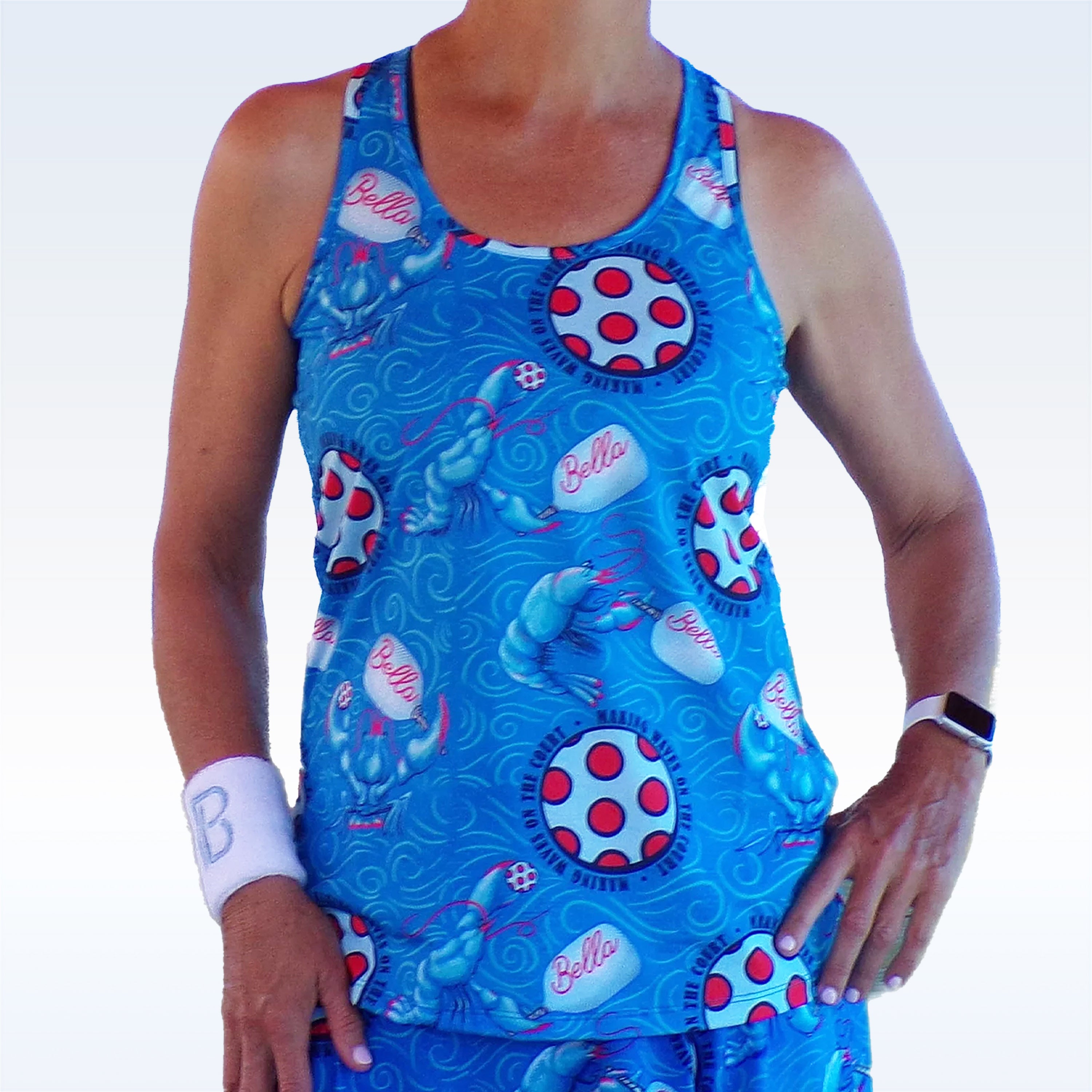 Blue racerback tank by Pickleball Bella, patterned with lobsters and pickleball elements, worn with a white wristband and smartwatch.