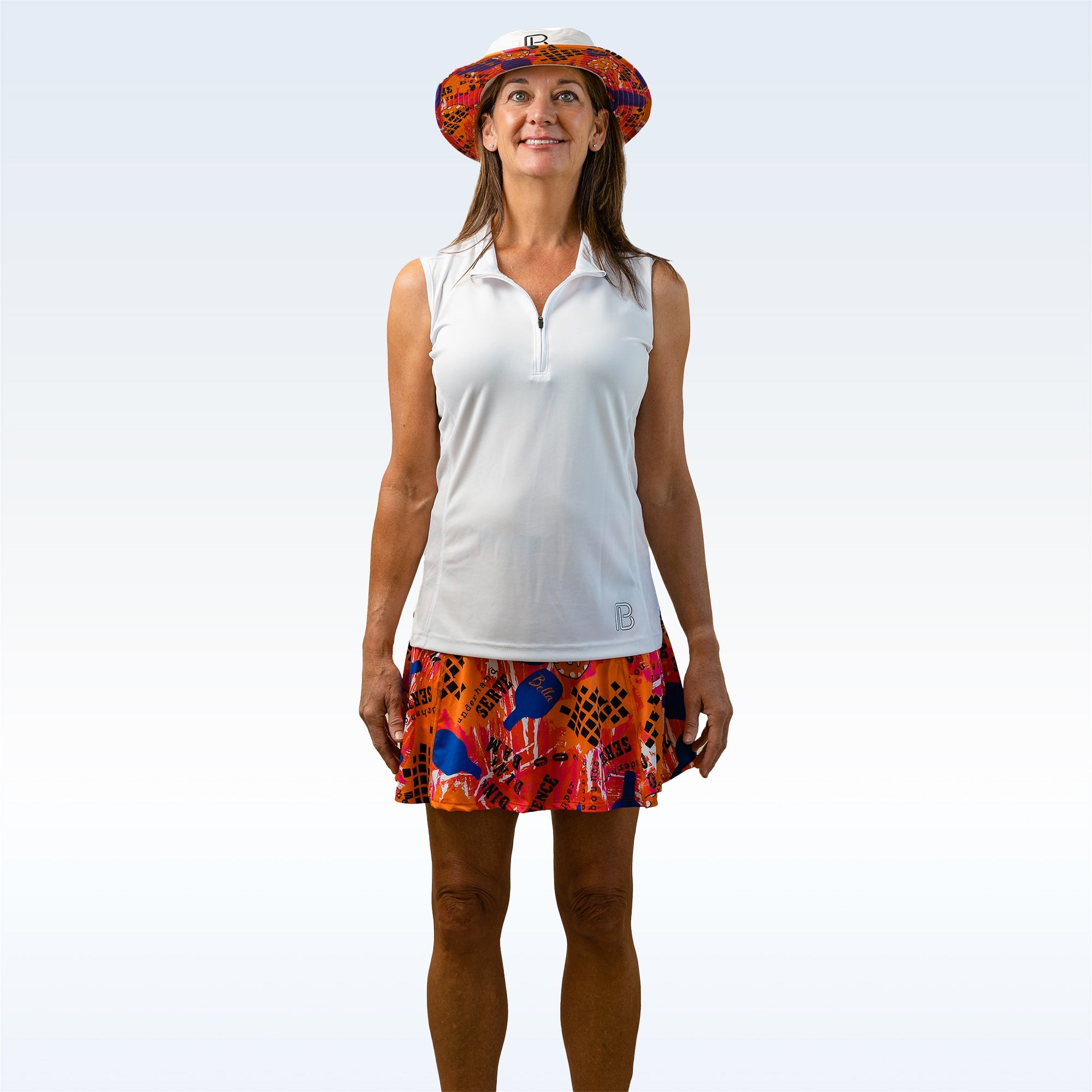 White 1/4 Zip Sleeveless by Pickleball Bella, featuring a small 'B' logo, worn with a colorful hat and skirt.