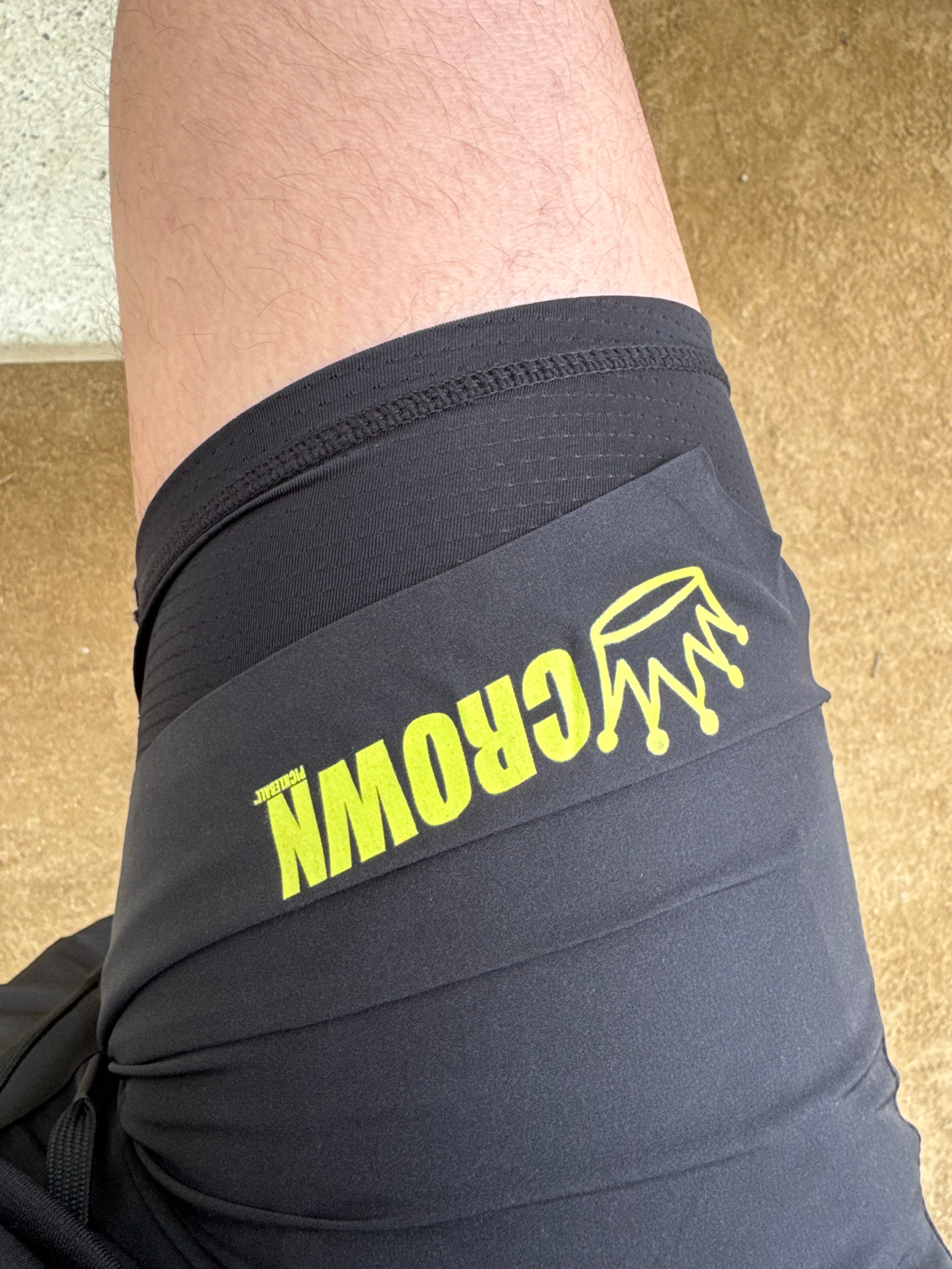 Person wearing black athletic shorts with yellow "Crown" logo.