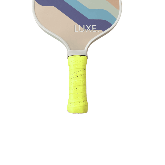 Close-up of a pickleball paddle with a yellow grip.
