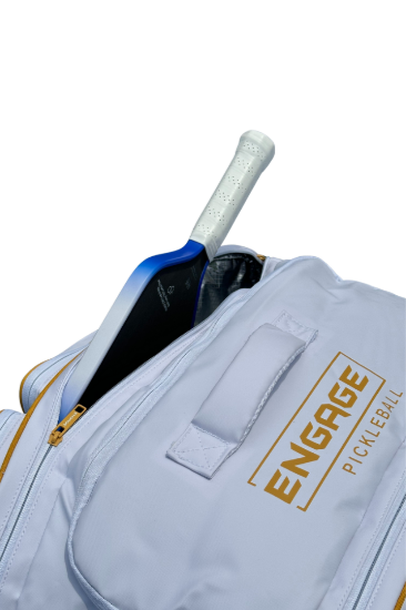 White Pro Team Bag by EngagePickleball, with gold zipper, logo, and a white and blue pickleball paddle inside.