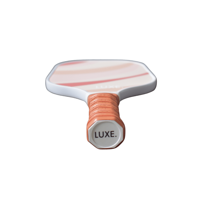 Pickleball paddle with pink and white design, orange grip, and "LUXE." logo.