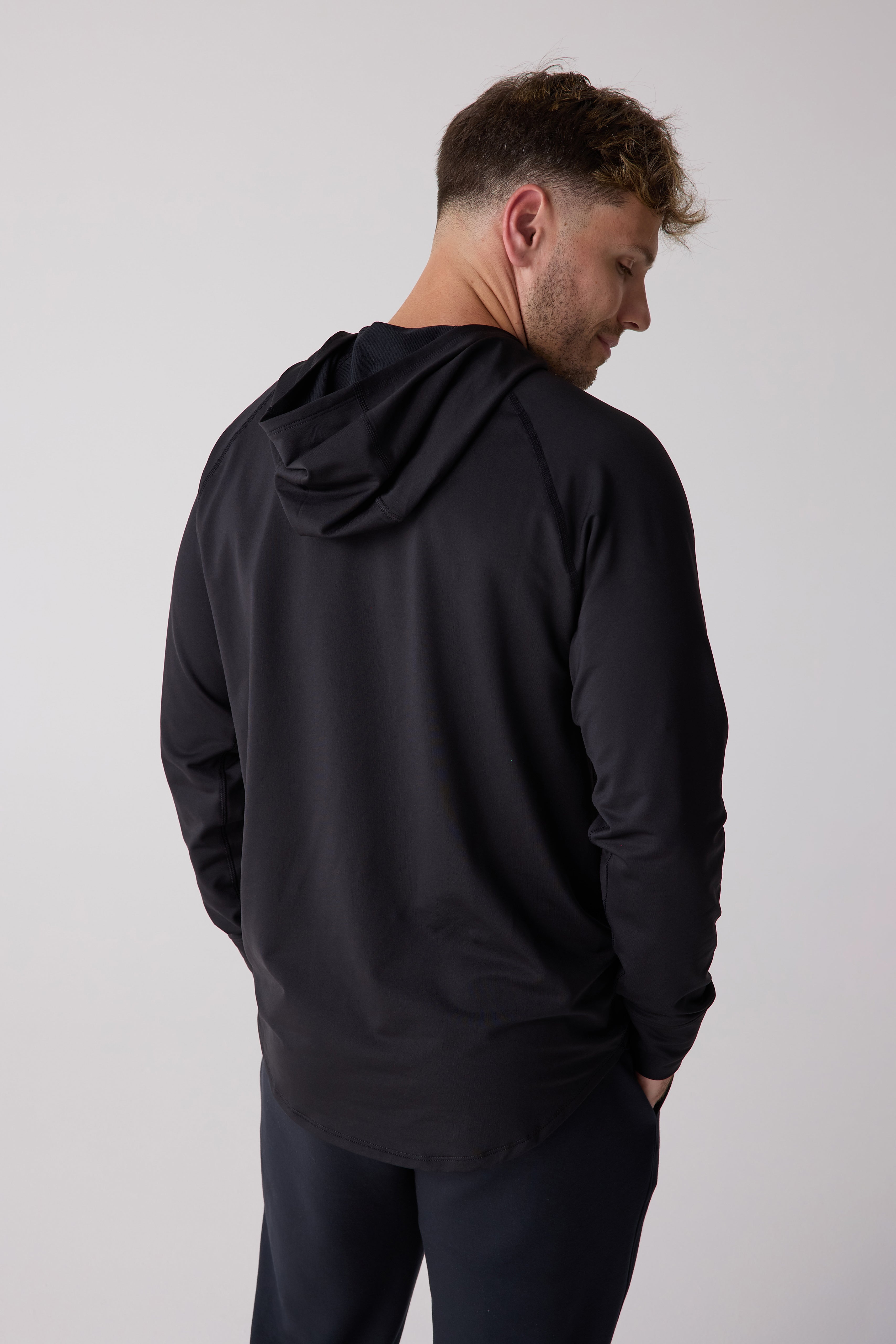 Black men's layering hoodie by Centerline Athletics, long-sleeve and hooded, seen from the back on a man.