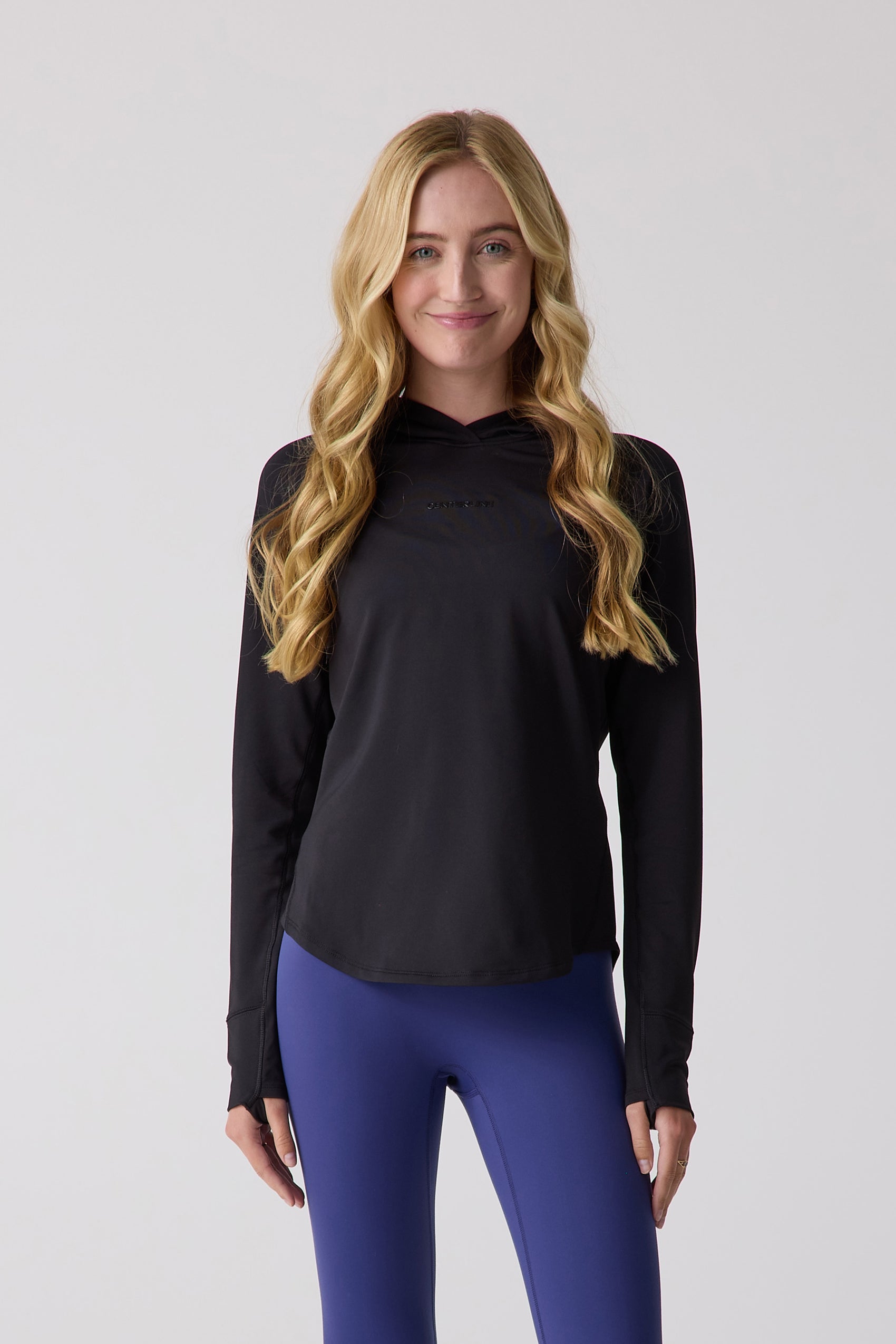 Black Women's Layering Hoodie by Centerline Athletics with subtle chest logo and thumbhole sleeves, paired with blue leggings.