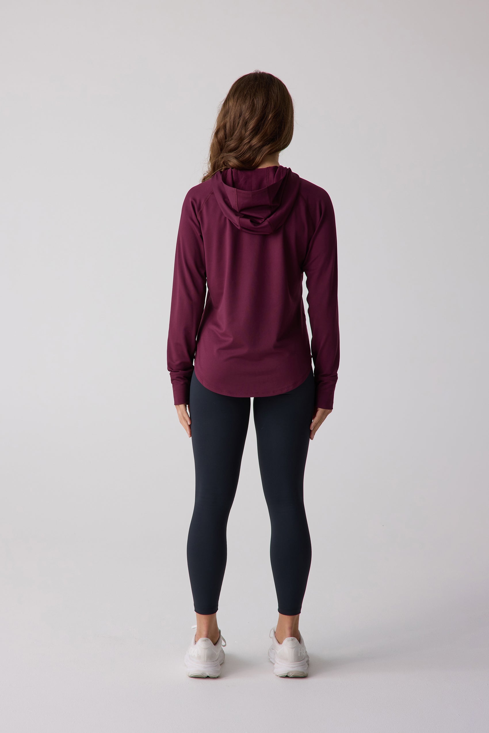 Maroon long sleeve layering hoodie by Centerline Athletics, featuring a hood and rounded hem, worn with black leggings.