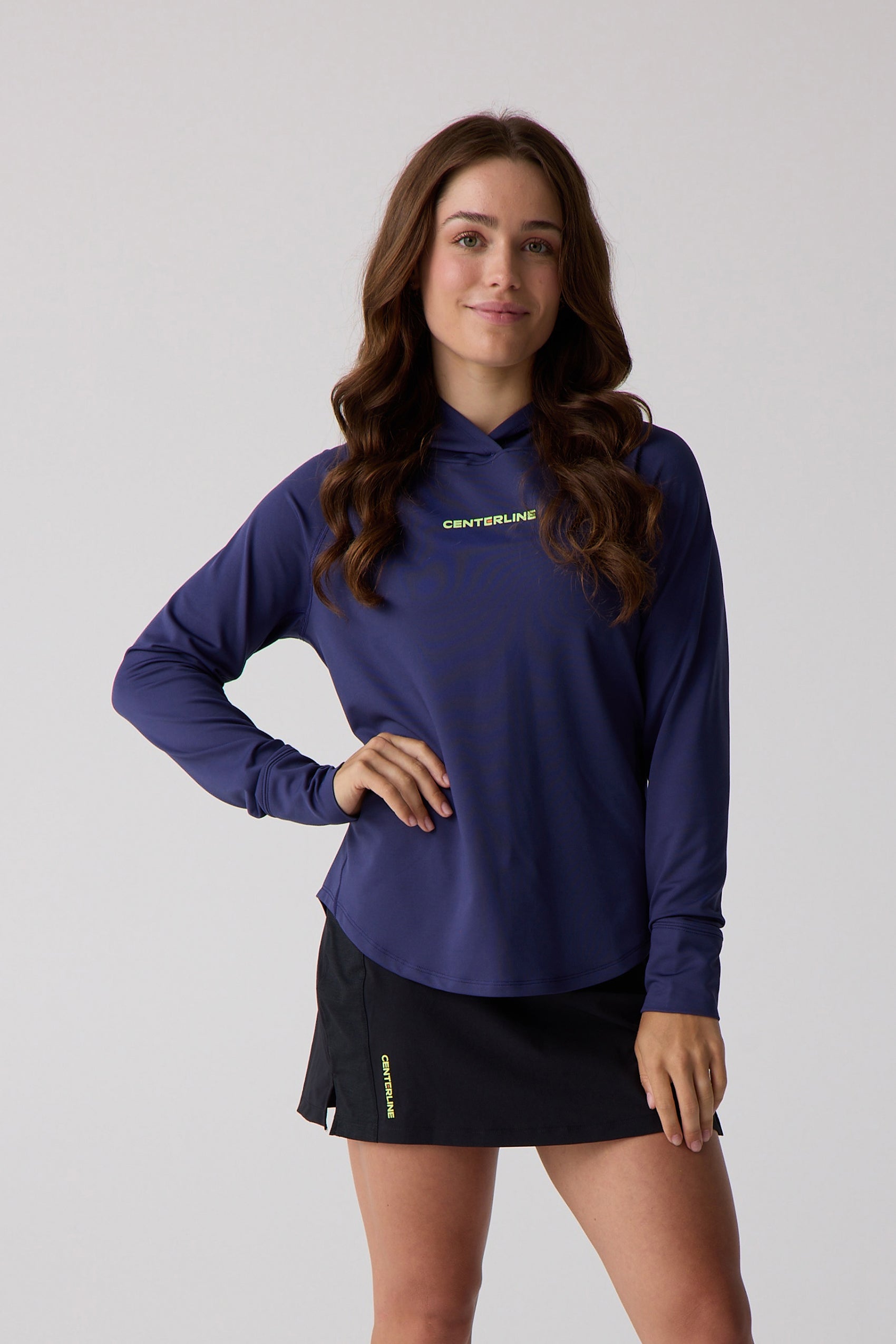 Navy blue women's layering hoodie by Centerline Athletics with lime green chest logo, styled with a black athletic skirt.